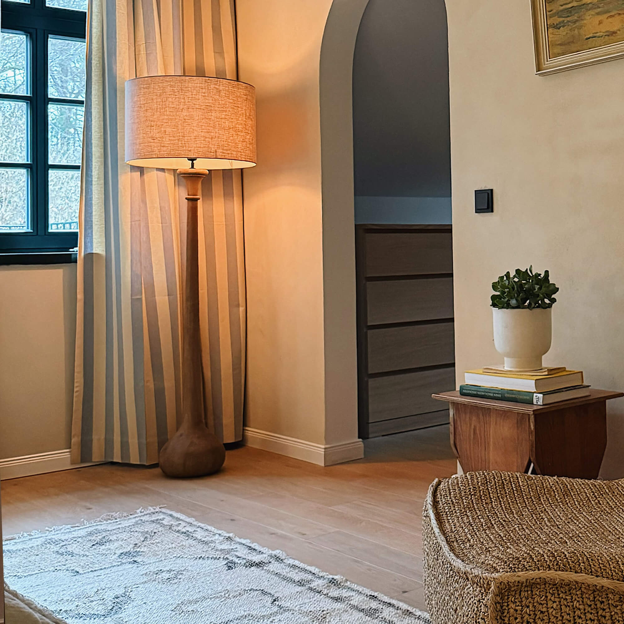 Houten vloerlamp met beige kap in gezellige woonkamer met natuurlijke decoratie