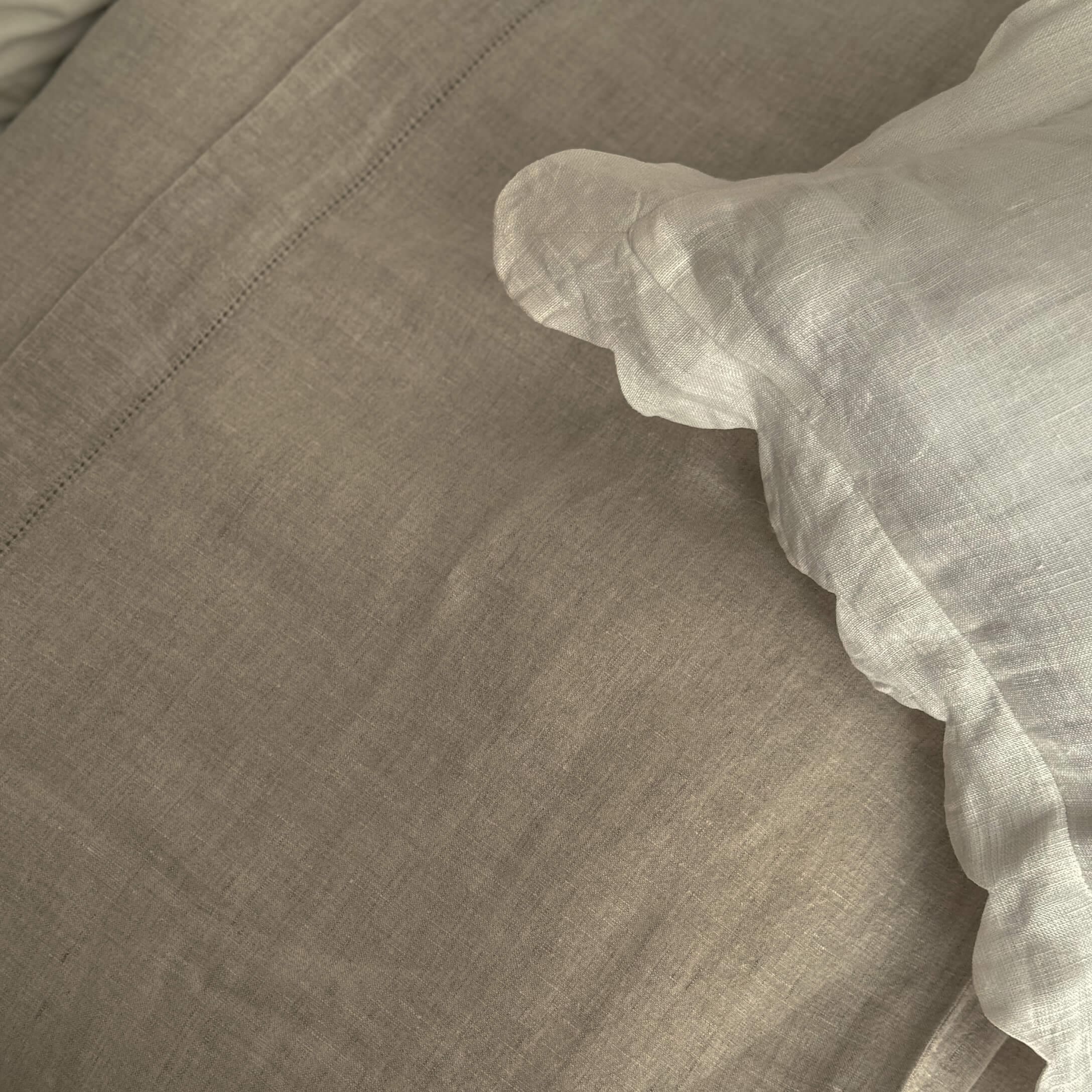 Beige linnen beddengoed met witte ruches, natuurlijke stof voor slaapkamer