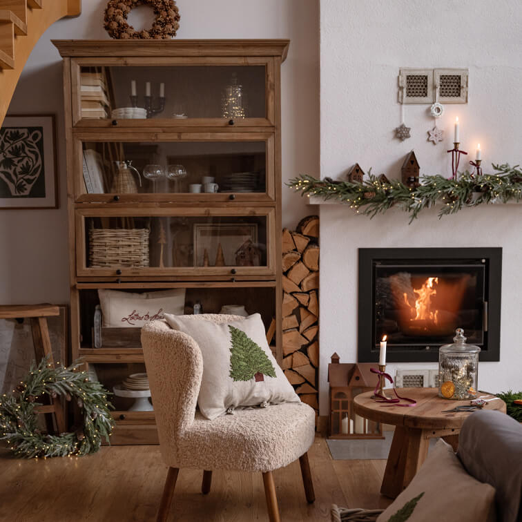 Gezellige woonkamer met crèmekleurige stoel, houten kast en kerstversierde open haard