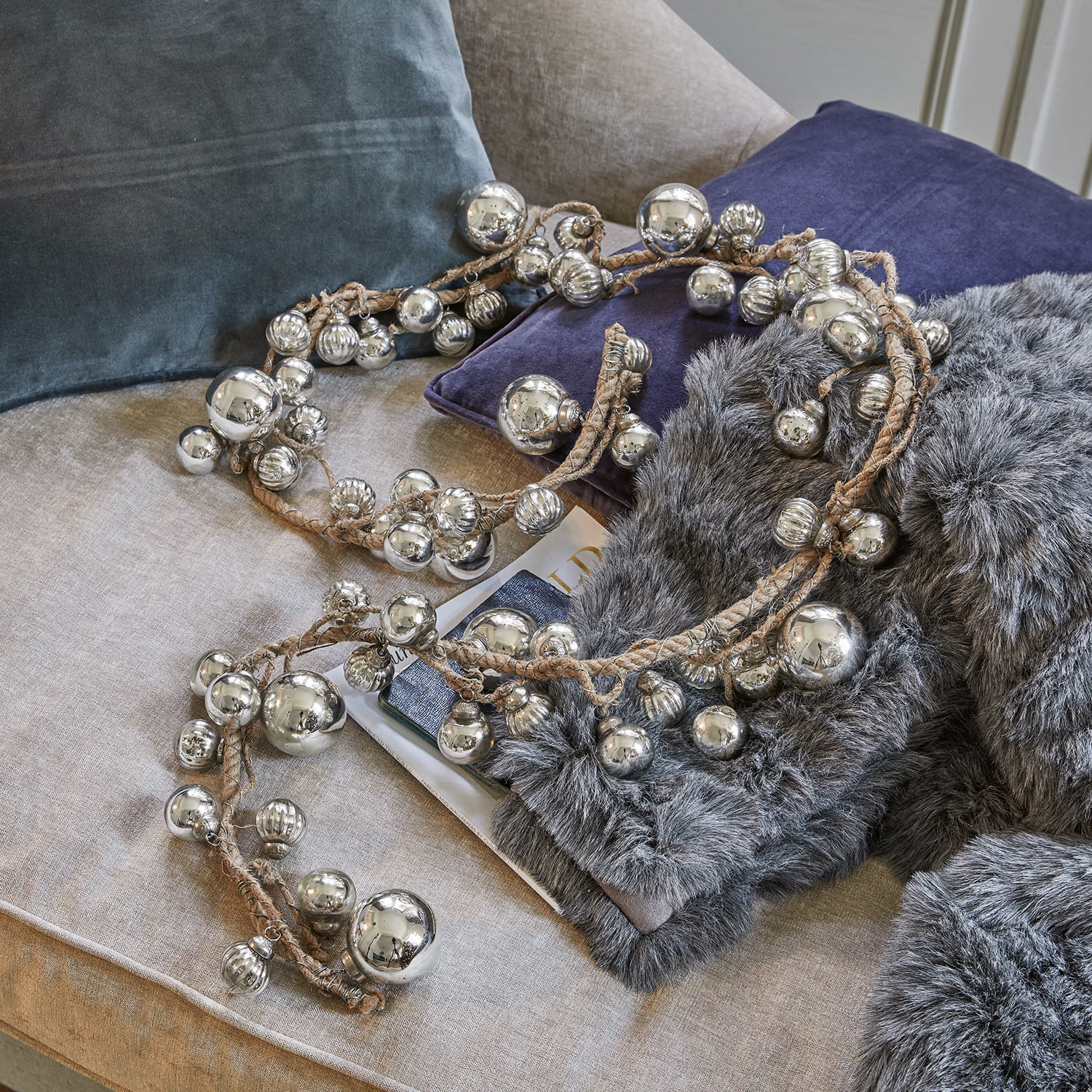 Guirlande Pearls Decoratieve ketting met zilverkleurige metalen ballen aan linnen touw op bank met kussens