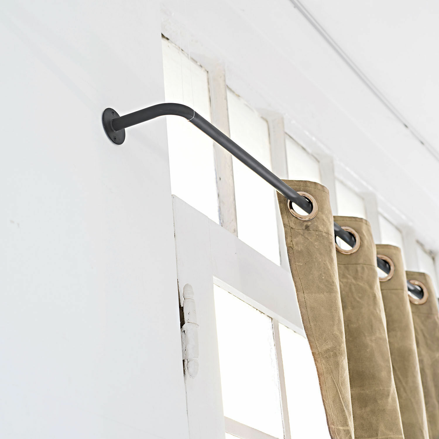 Gordijnroede Omara Zwarte metalen gordijnroede met beige gordijnen met ringen voor een wit raam