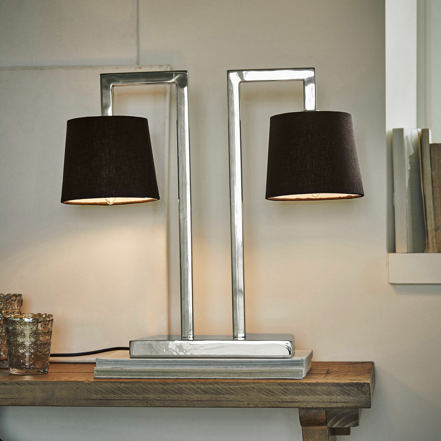 Moderne tafellamp met metalen voet en twee zwarte lampenkappen op houten tafel