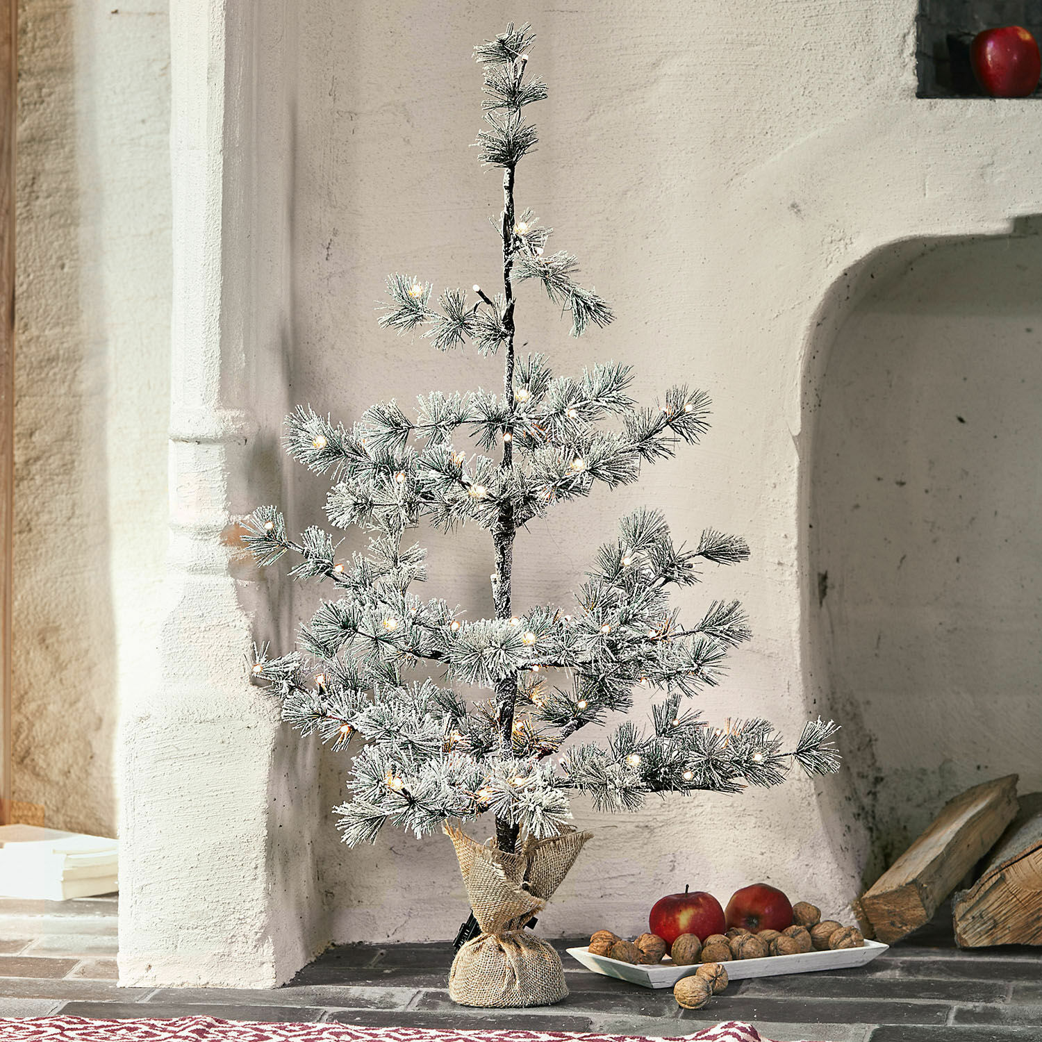 Kerstboom Falkirk Kleine kunstkerstboom met besneeuwde takken en LED-lichtjes in jute zak op de vloer
