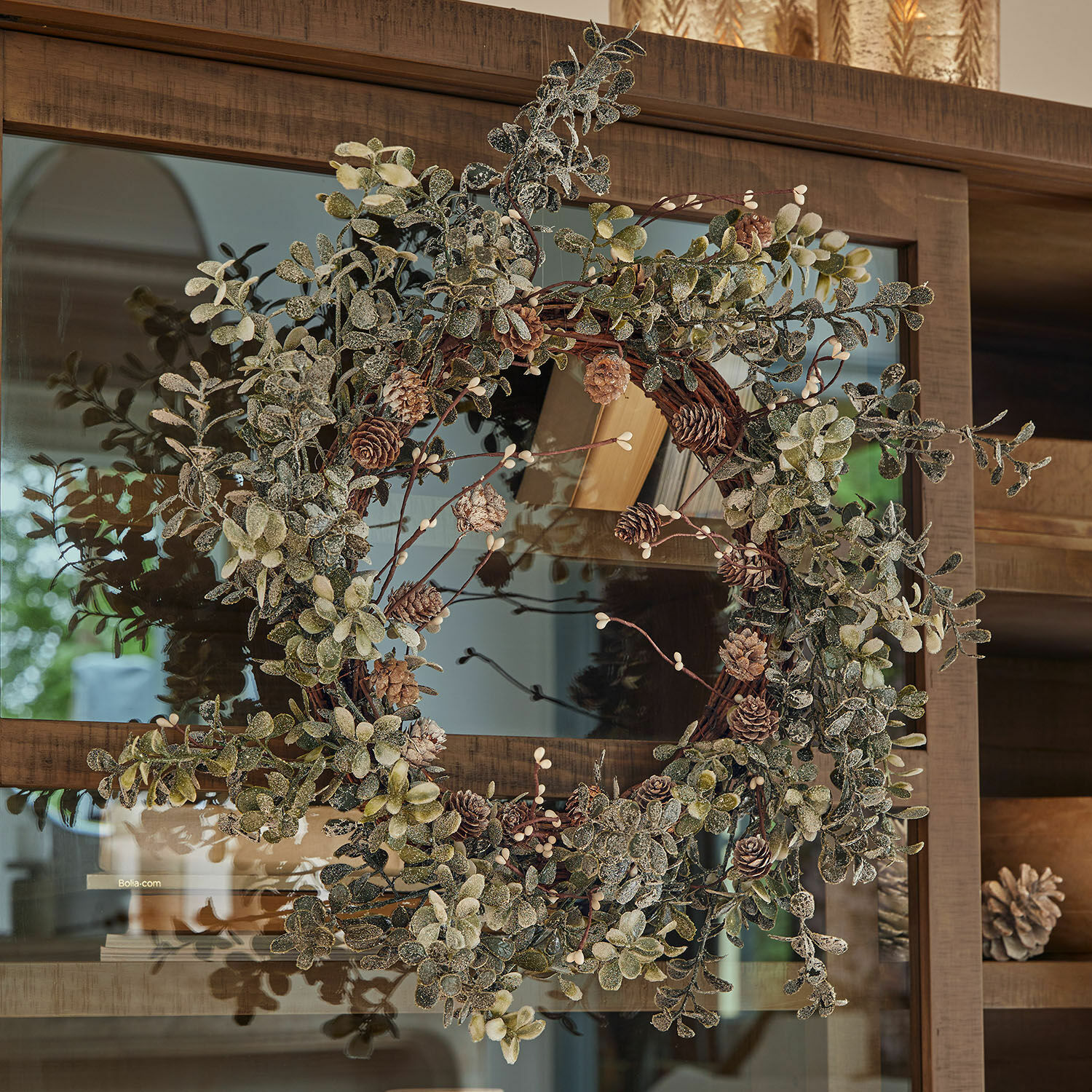 Krans Veloume Decoratieve krans van groene bladeren en dennenappels aan houten deur, feestelijke decoratie