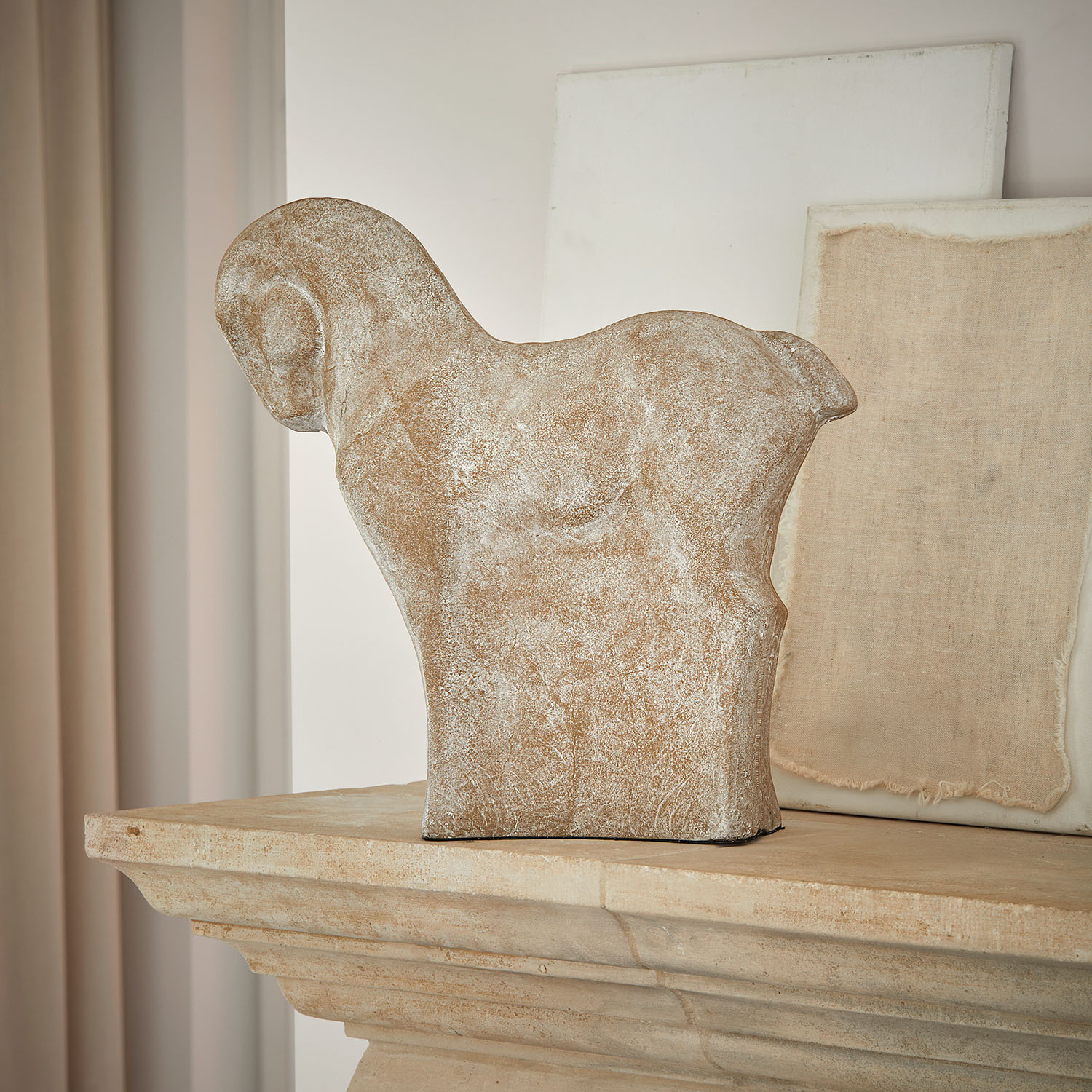 Decoratief paardenbeeld van beige steen op rustieke stenen schoorsteenmantel