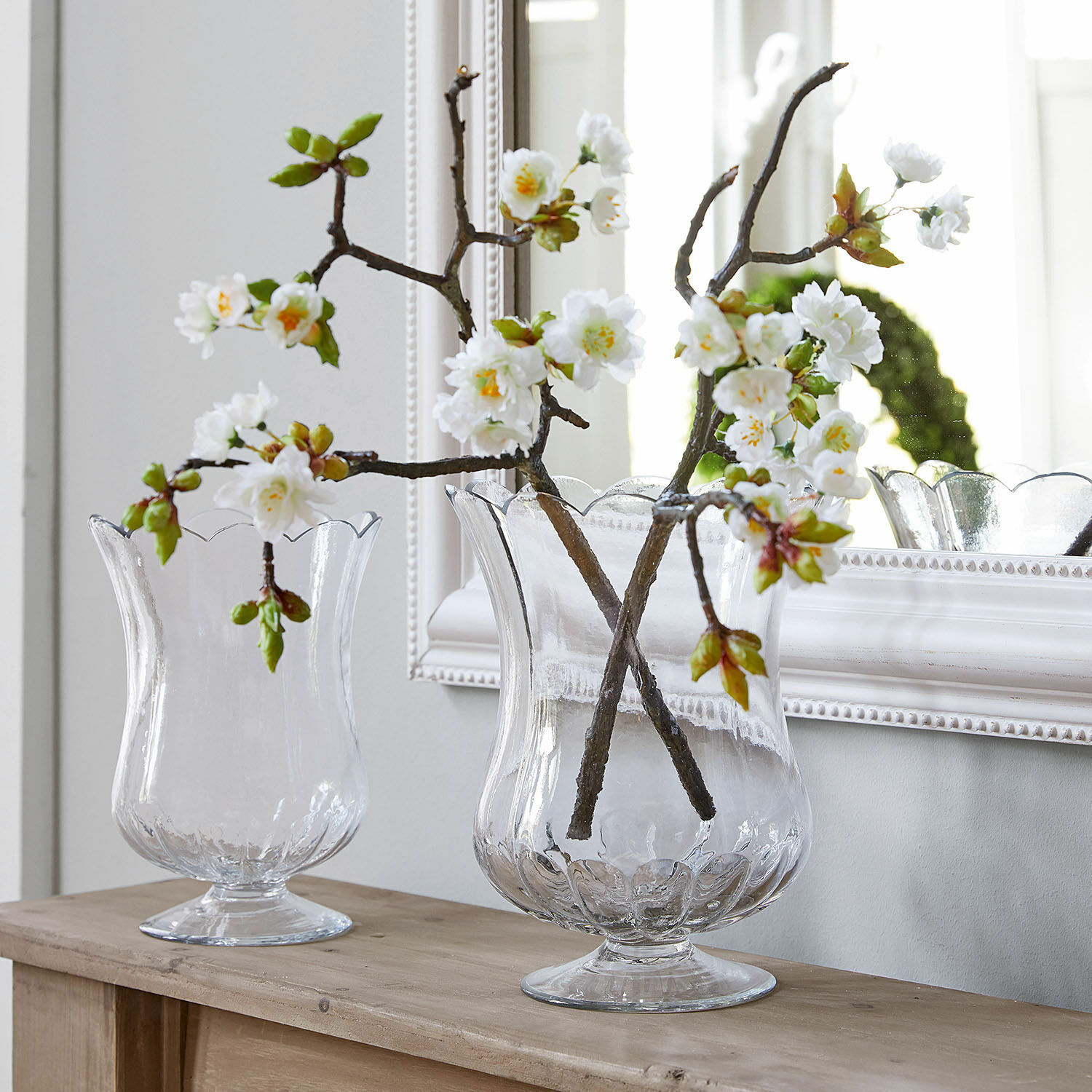 Sierbloem set van 2 Gráda Transparante glazen vazen met golvende rand op houten tafel met witte decoratieve bloemen