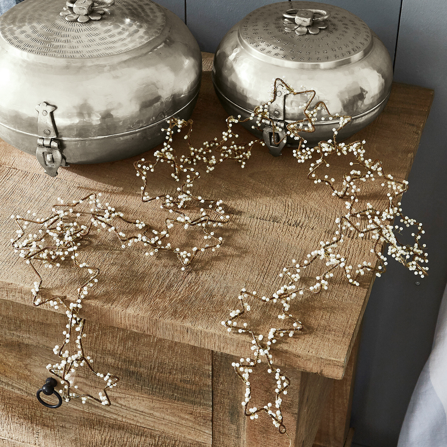 Decoratieve sterrenketting met witte parels op houten tafel, feestelijke kerstversiering