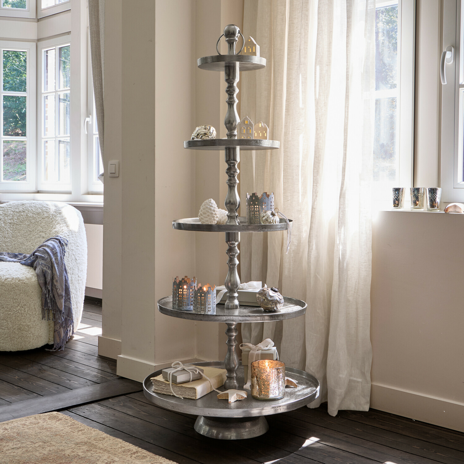 Vijflaagse metalen kerstdecoratie met groene takken en gouden ballen in woonkamer