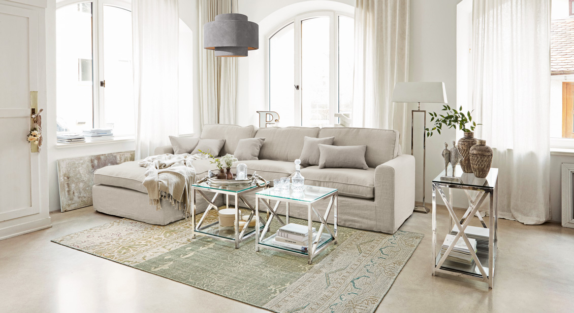 Beige linnenlook bank met kussens en metalen tafels in lichte woonkamer
