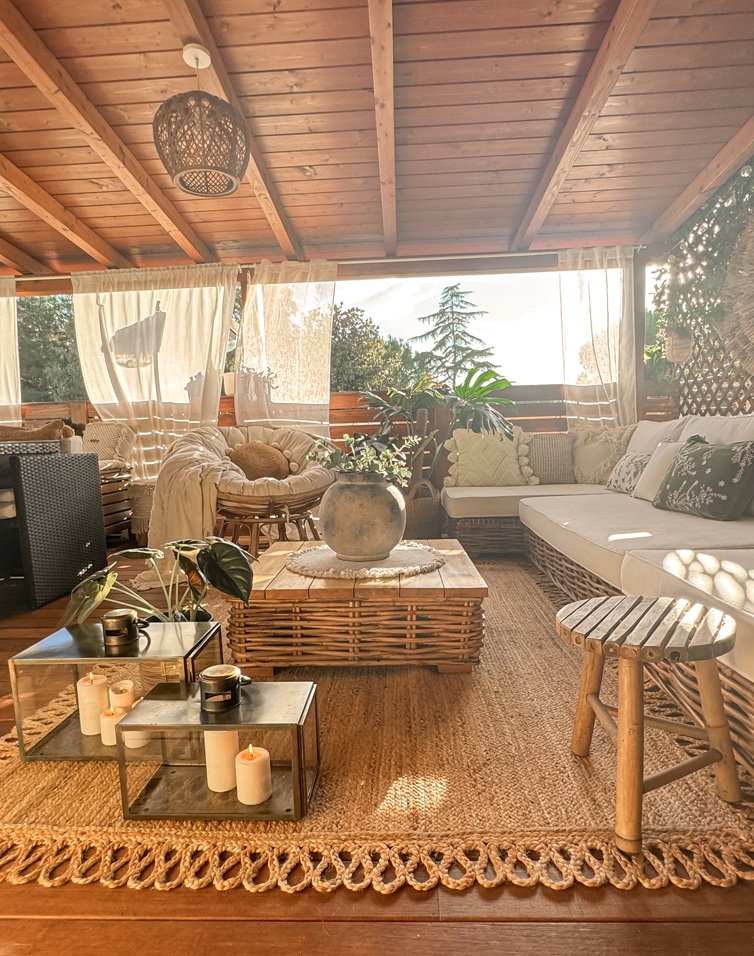 Gezellig terras met rotanmeubels, houten tafel en natuurlijke jute vloerkleed in warm licht