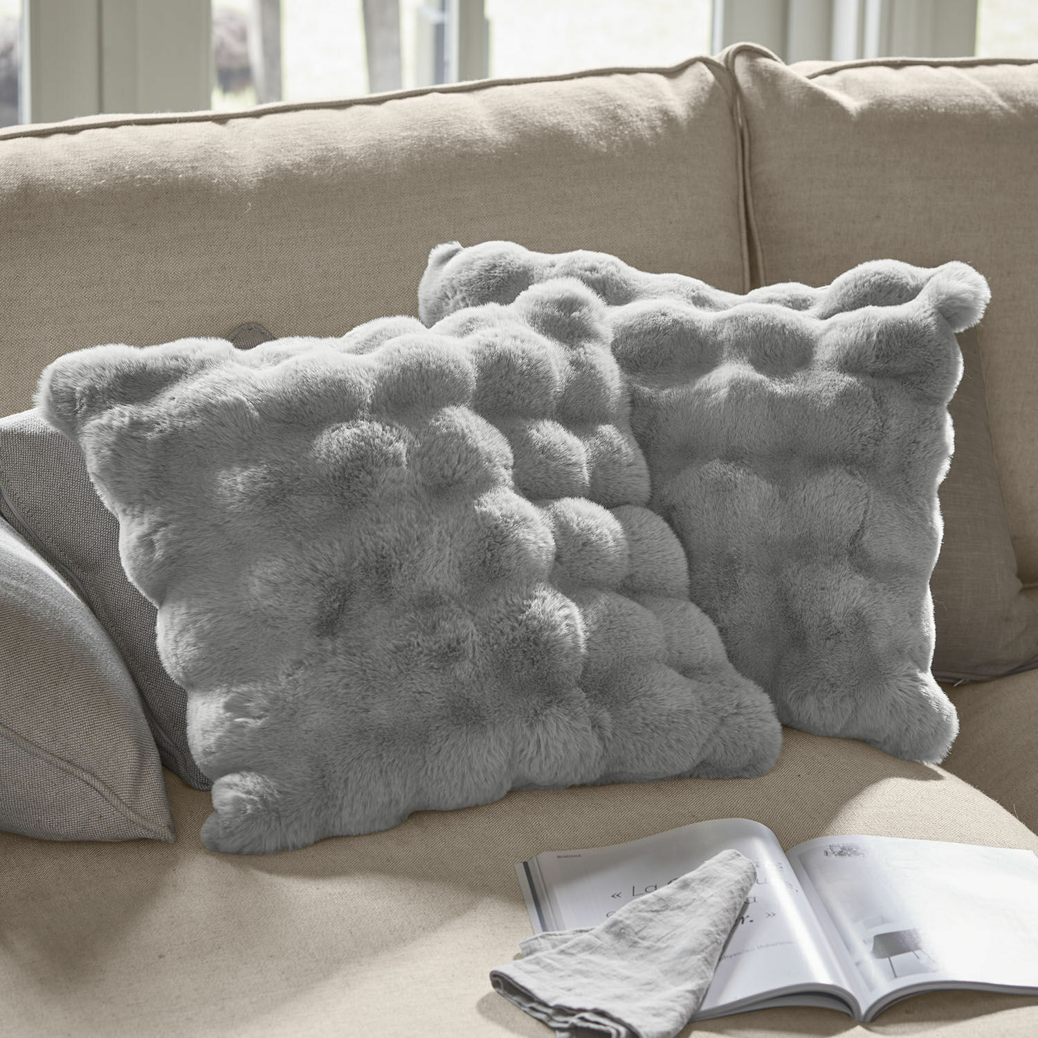 Kussenhoes set van 2 Zalina Zachte grijze sierkussens van imitatiebont op beige bank, perfect voor een gezellige woonkamer