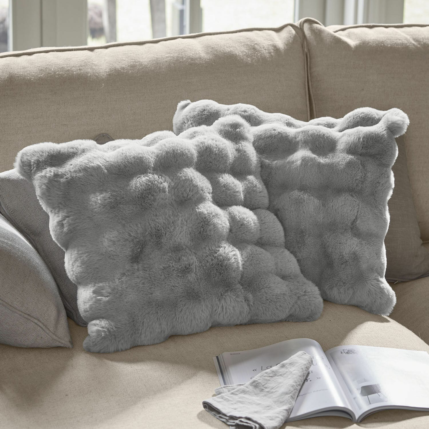 Kussenhoes set van 2 Zalina Zachte grijze sierkussens van imitatiebont op beige bank, perfect voor een gezellige woonkamer