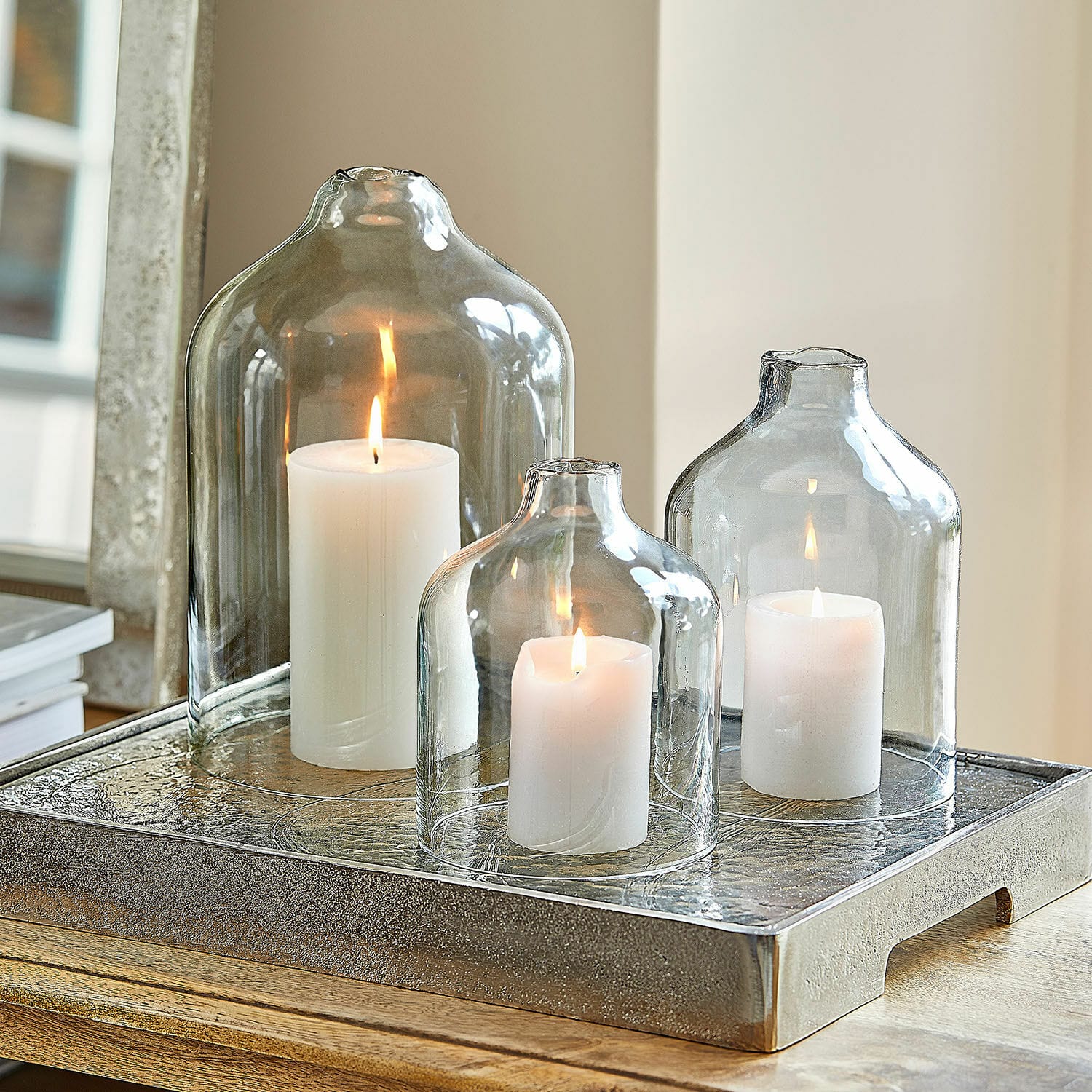 Windlicht set van 3 Xalvent Set van drie transparante glazen stolpen met witte kaarsen op een decoratief metalen dienblad