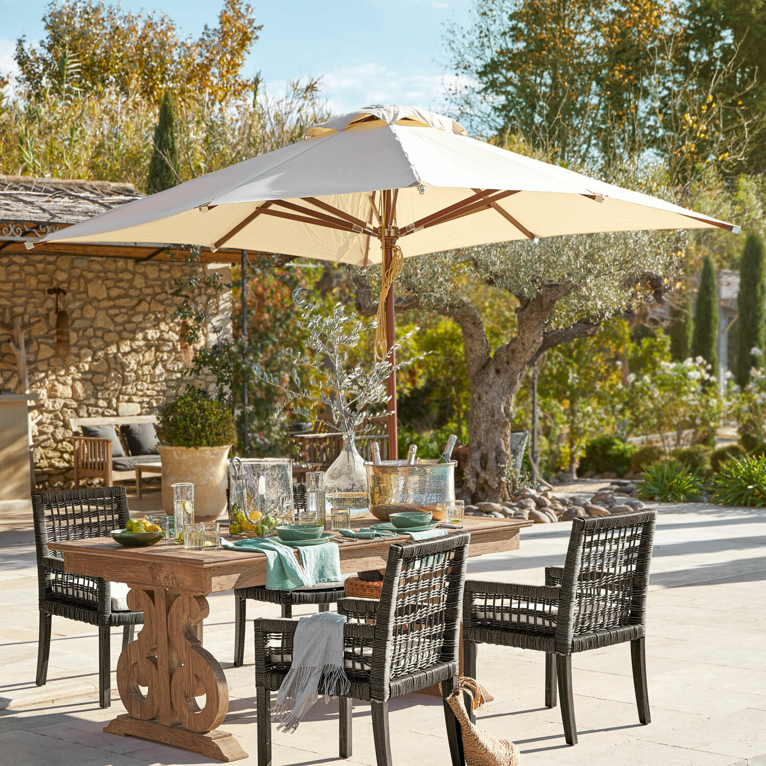 Parasol Brent Tuinmeubelset met houten tafel en zwarte rotan stoelen onder een beige parasol