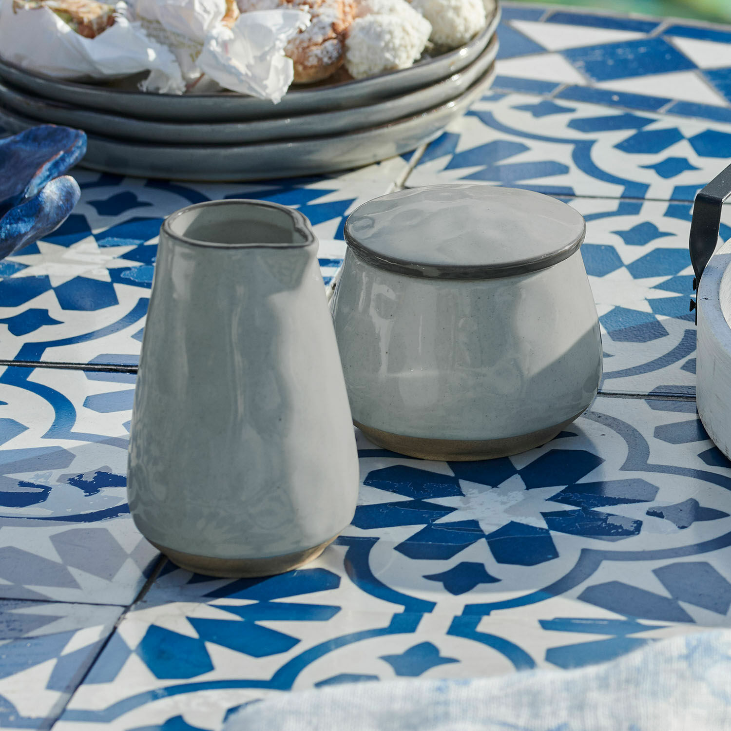 Suikerpotje en melkkannetje Biarré Grijze keramische suikerpot en melkkan op blauw-wit patroon tafel in eetkamer