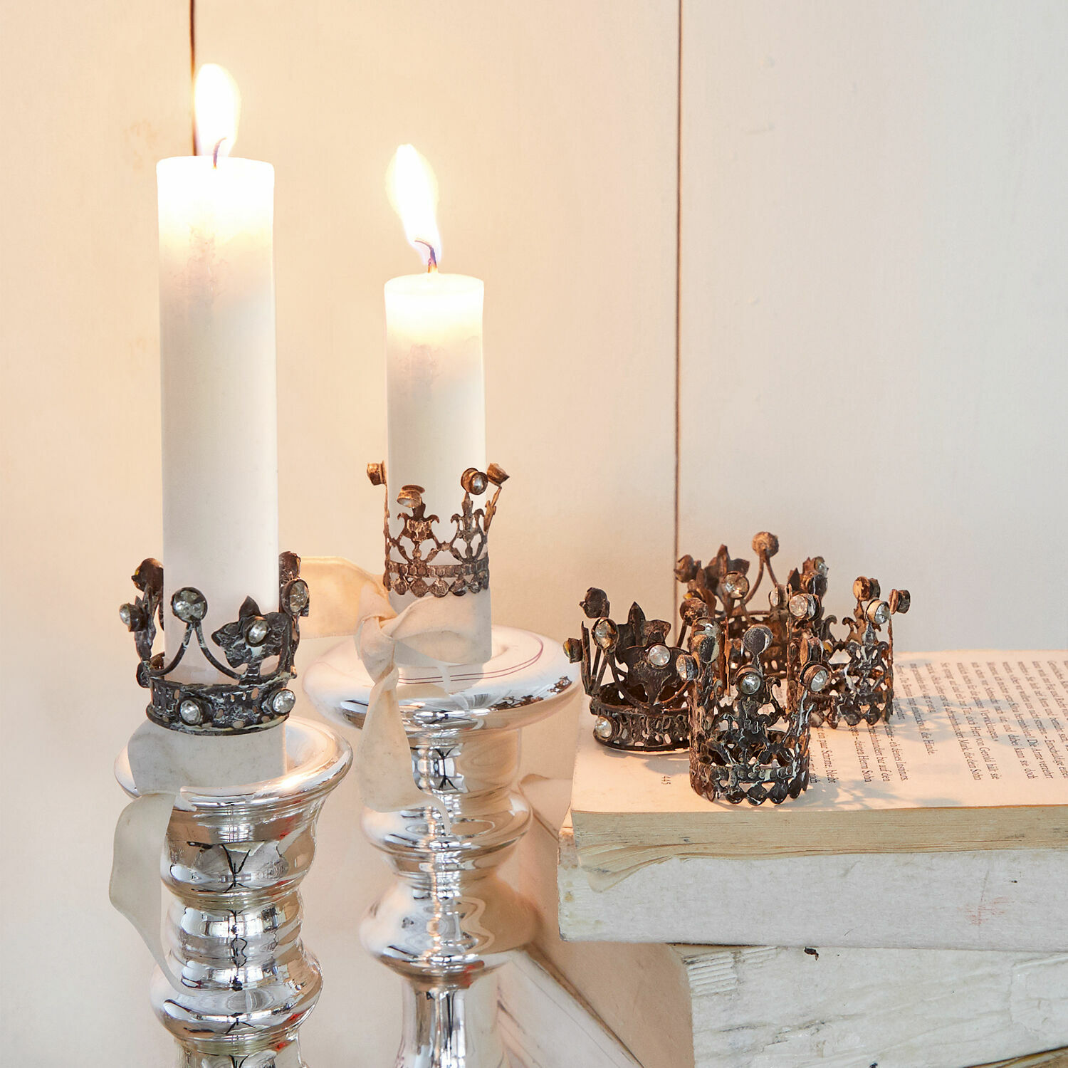 Witte kaarsen met metalen kroonversieringen op zilveren kandelaars, sfeervolle interieurdecoratie