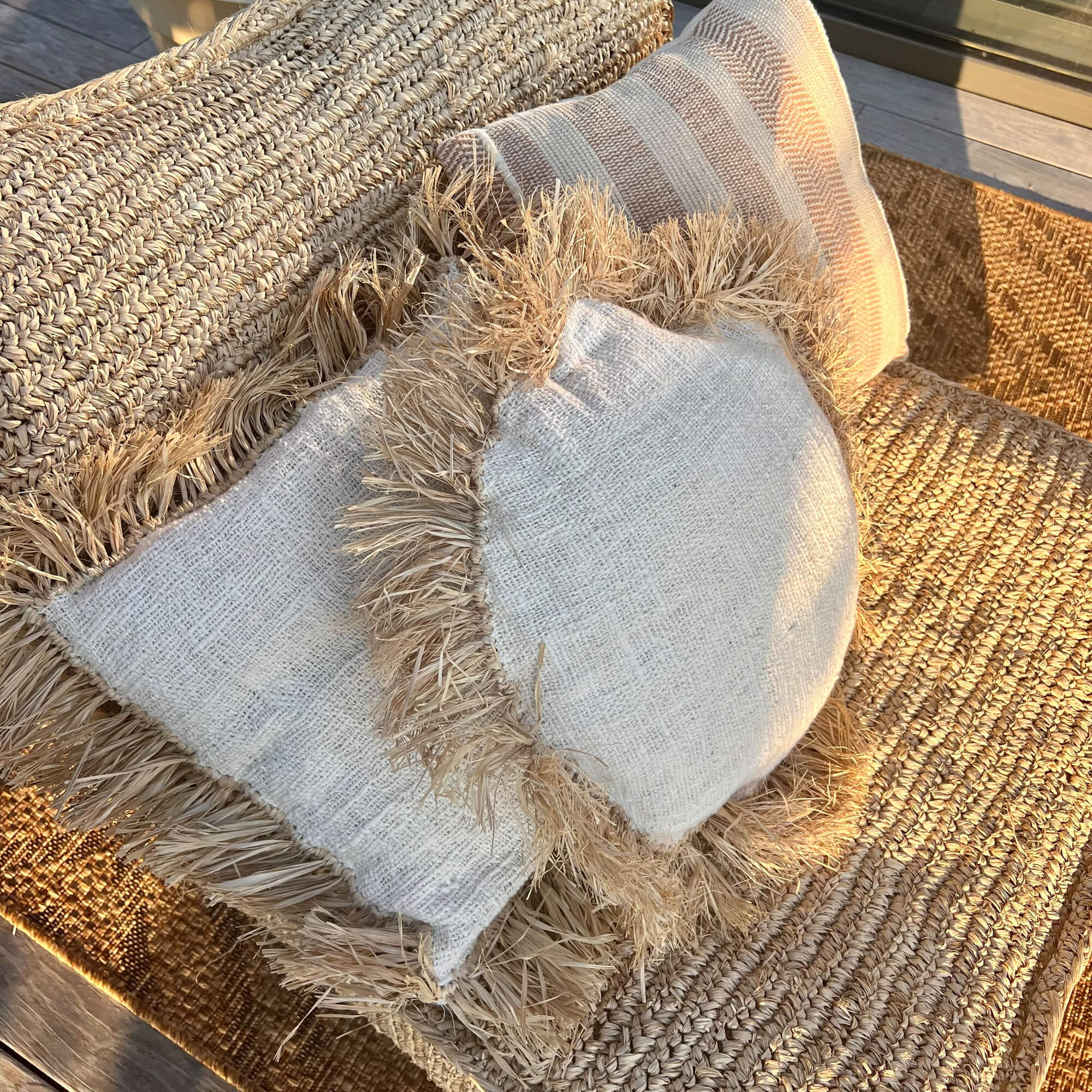Natuurlijke sierkussens met franjes op beige gevlochten zitting van textiel en riet