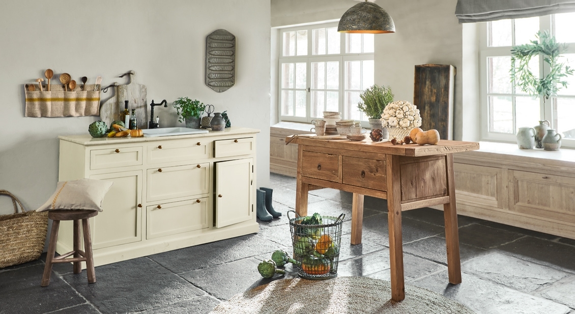 Rustieke keuken met houten tafel en crèmekleurige kast op zwarte stenen vloer, natuurlijke sfeer