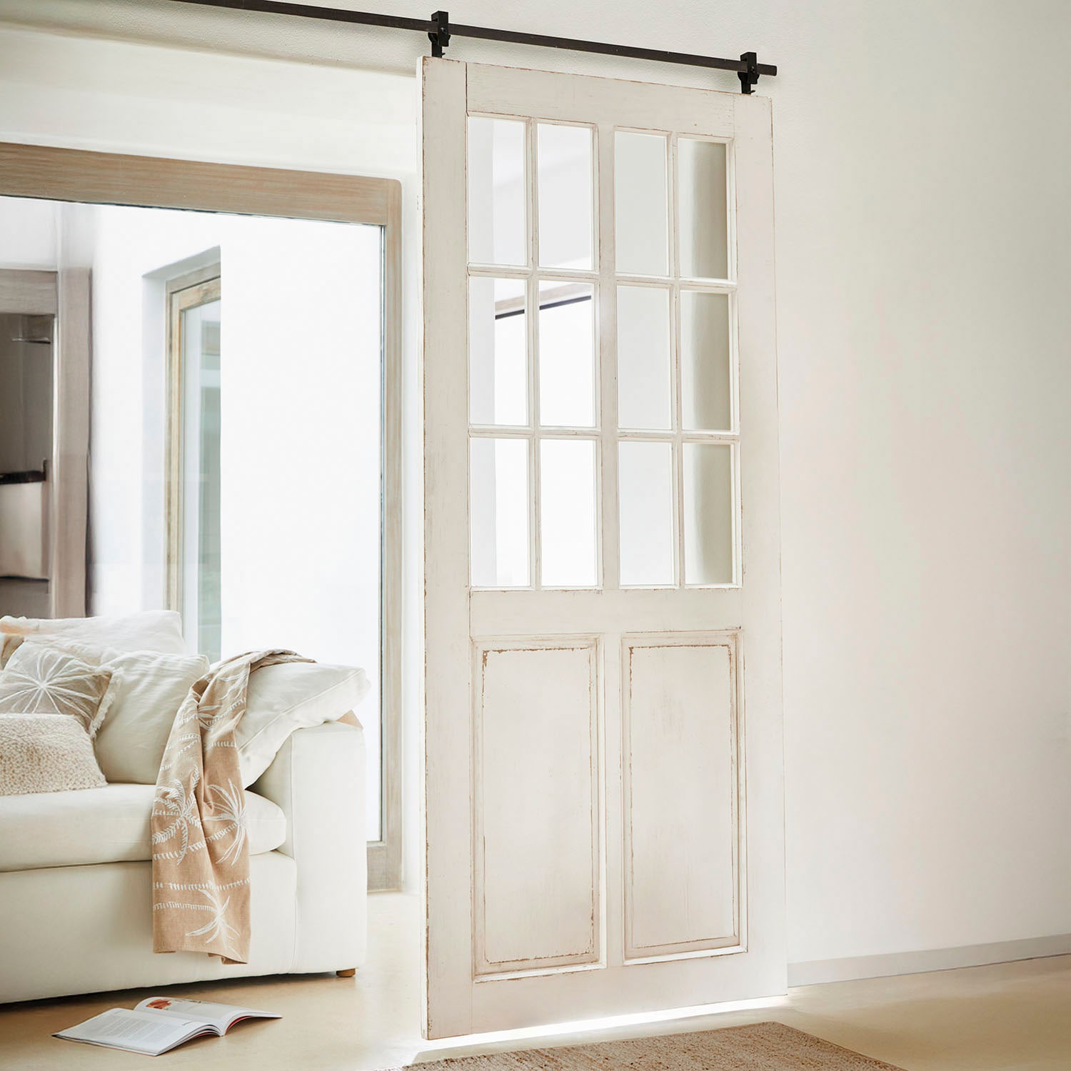 Witte houten schuifdeur met vintage glas in een lichte, moderne woonkamer