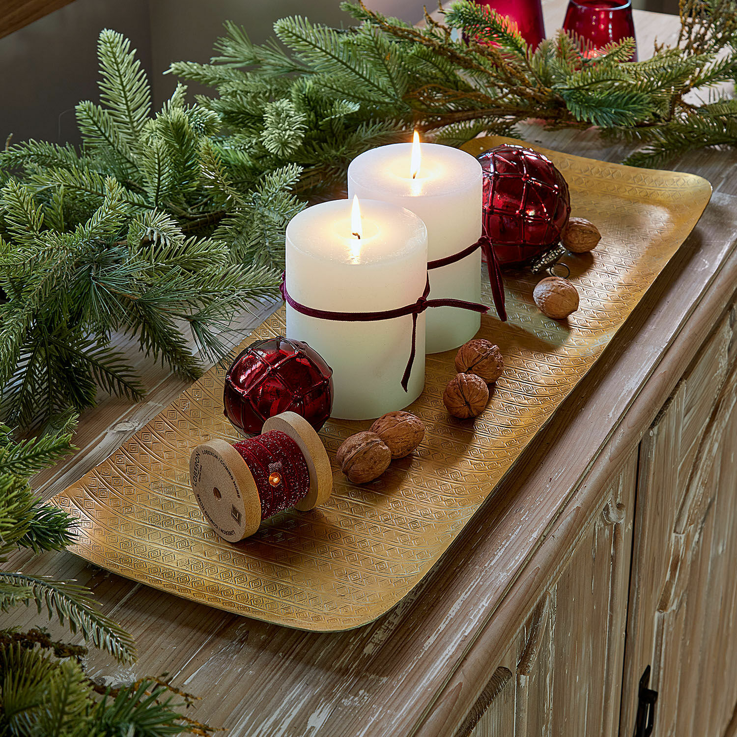 Gouden metalen schaal met witte kaarsen, rode decoraties en noten op houten tafel, kerstdecoratie