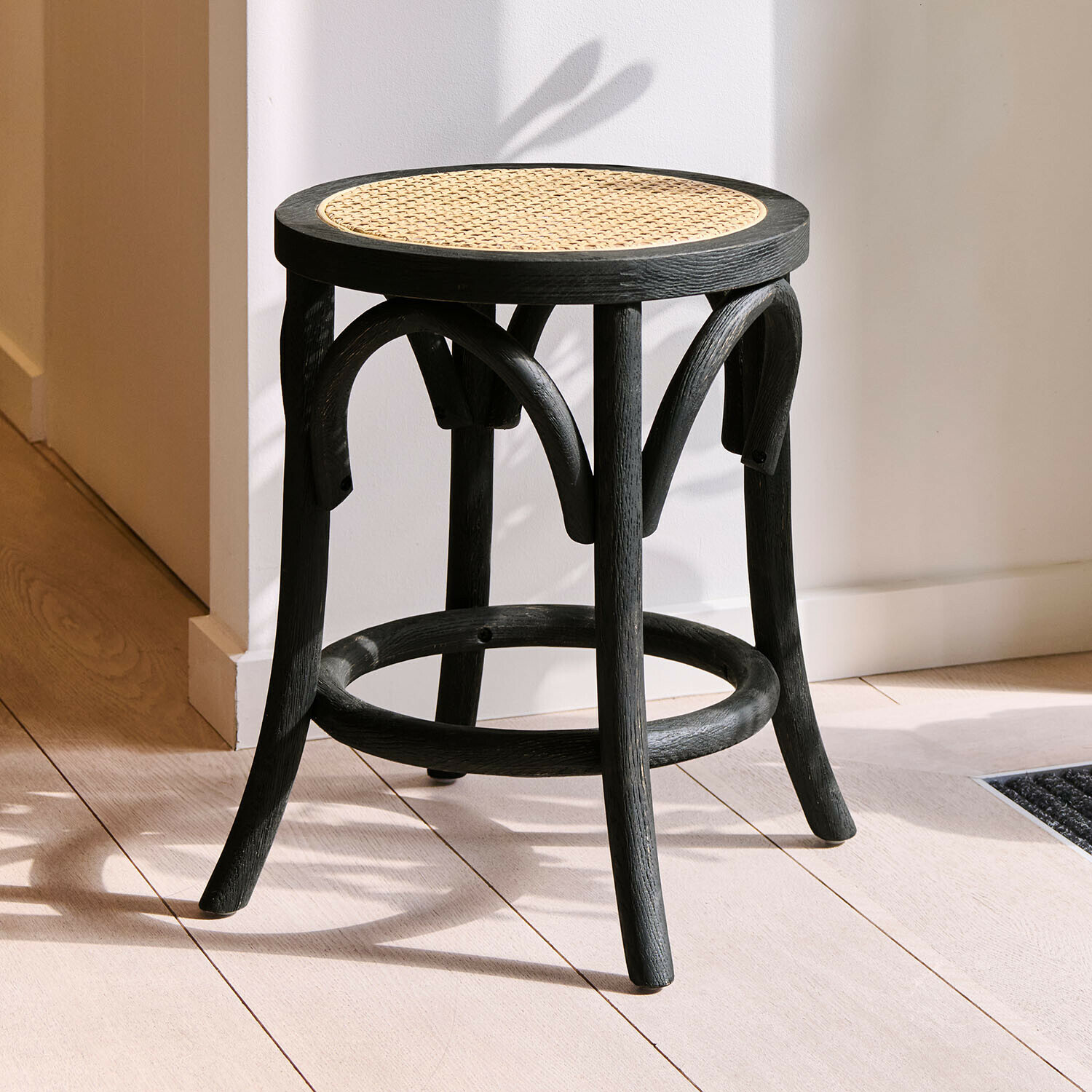 Zwarte houten kruk met rond gevlochten zitvlak, modern meubelstuk voor binnen