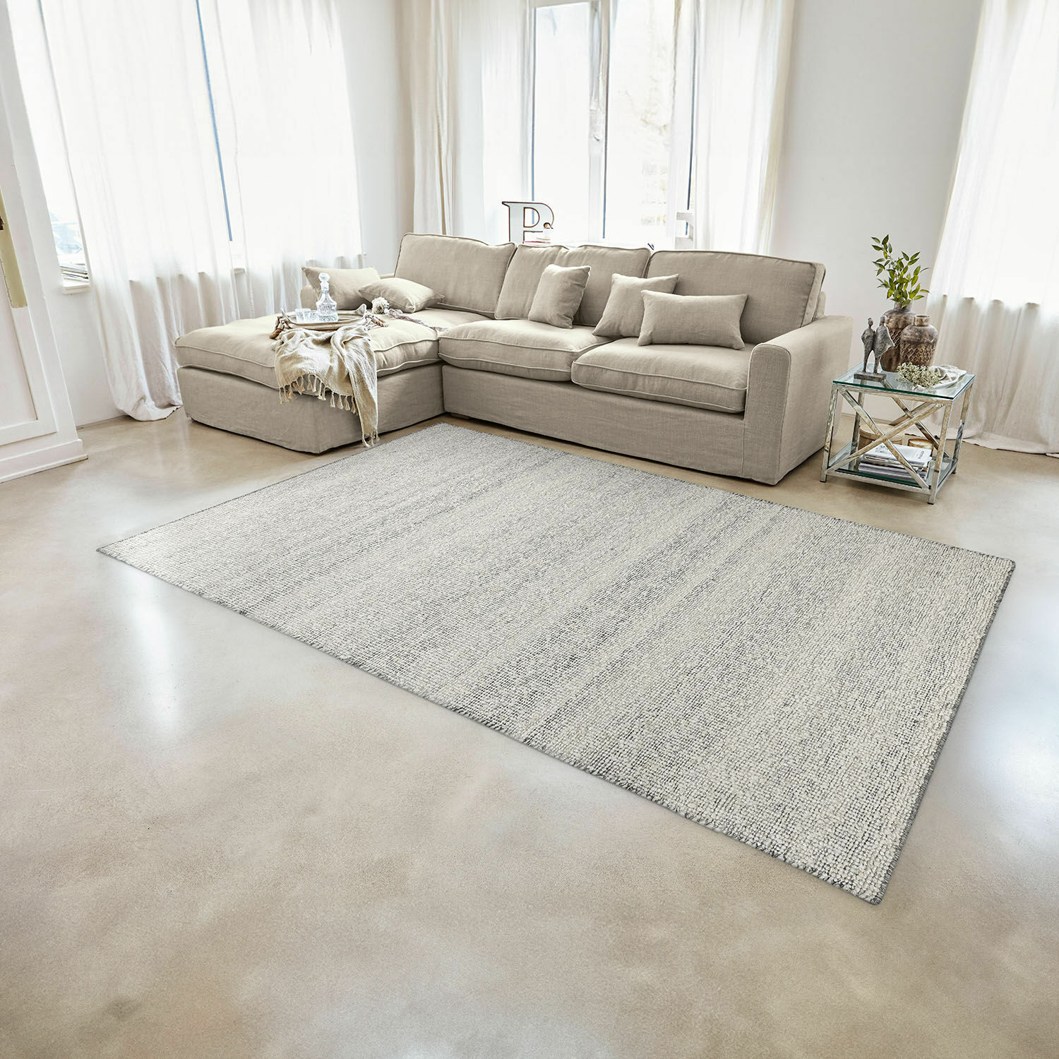 Beige stoffen hoekbank in lichte woonkamer met lichtgrijs vloerkleed op de vloer