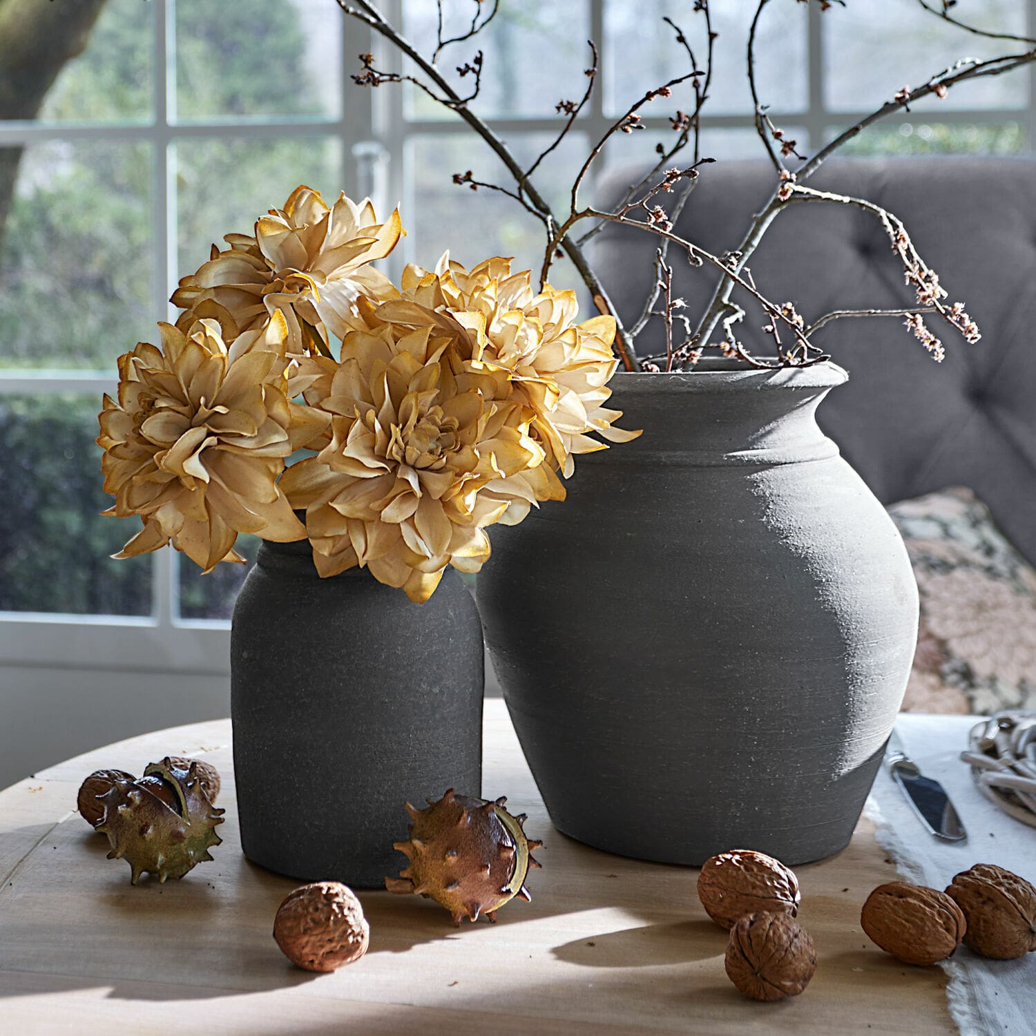 Sierbloem set van 4 Cappellina Twee donkergrijze keramische vazen met gedroogde bloemen en noten op een lichte houten tafel
