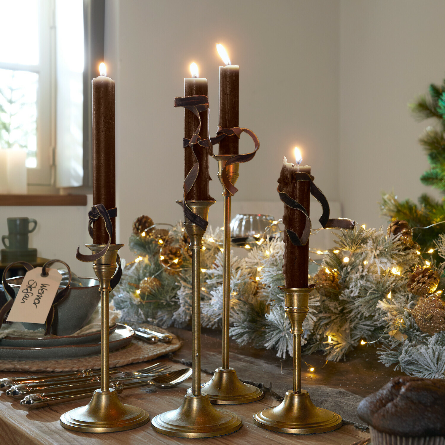 Kaars set van 12 Bauceau Set van vier gouden kandelaars met bruine kaarsen en decoratieve linten op feestelijke tafel