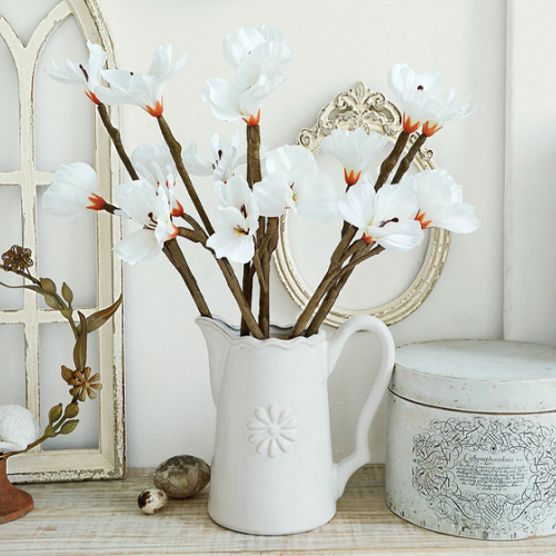 Witte keramische kan met decoratieve bloemen op houten tafel, vintage stijl, interieurdecoratie