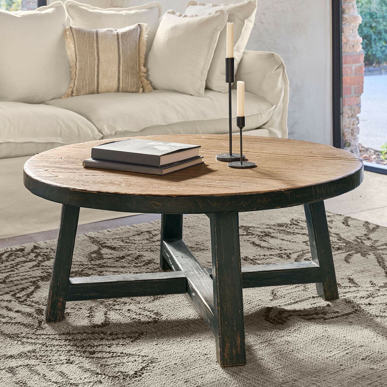 Ronde salontafel van natuurlijk en zwart hout op een vloerkleed in de woonkamer