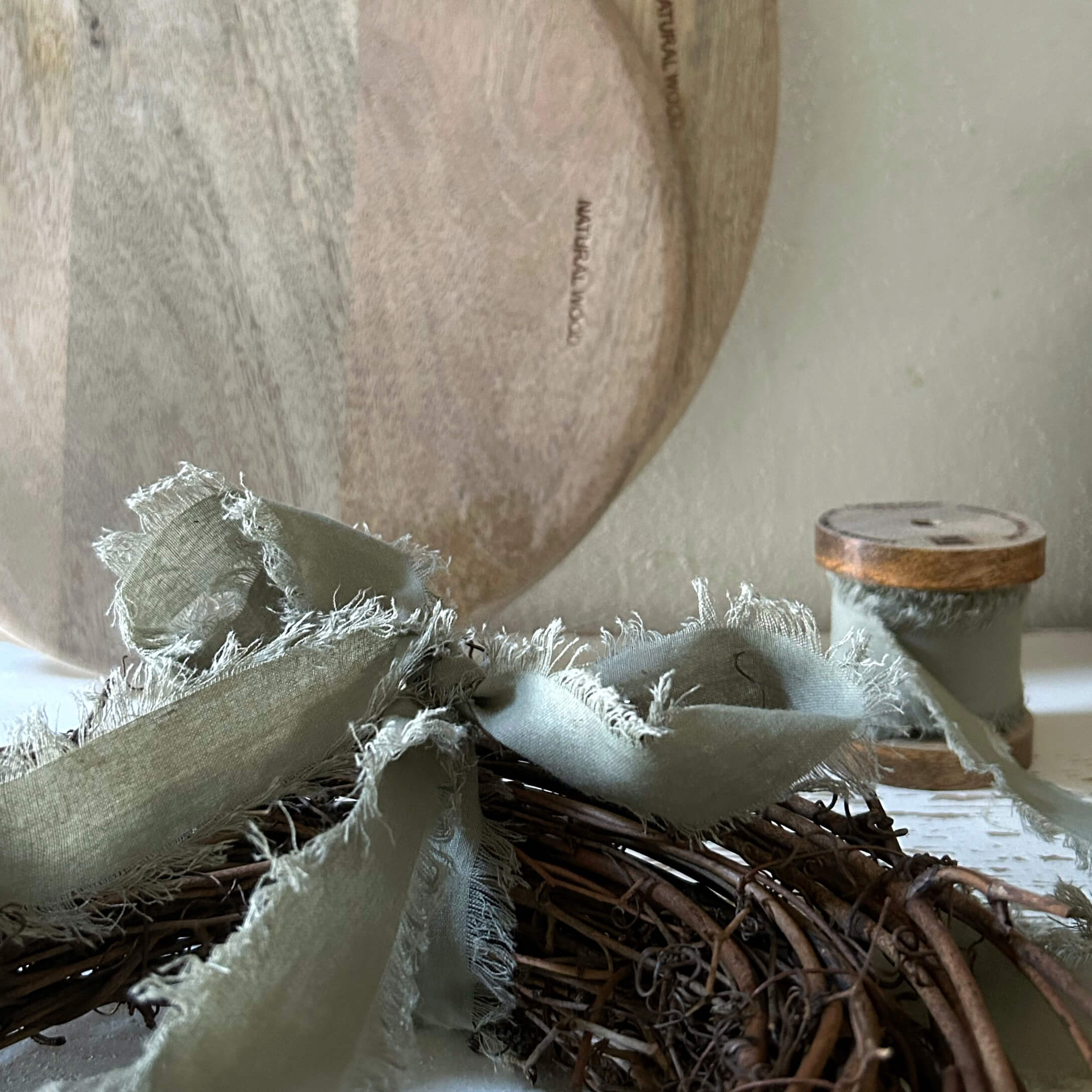 Natuurlijke houten schaal met grijs linnen lint op een wilgenkrans voor interieurdecoratie