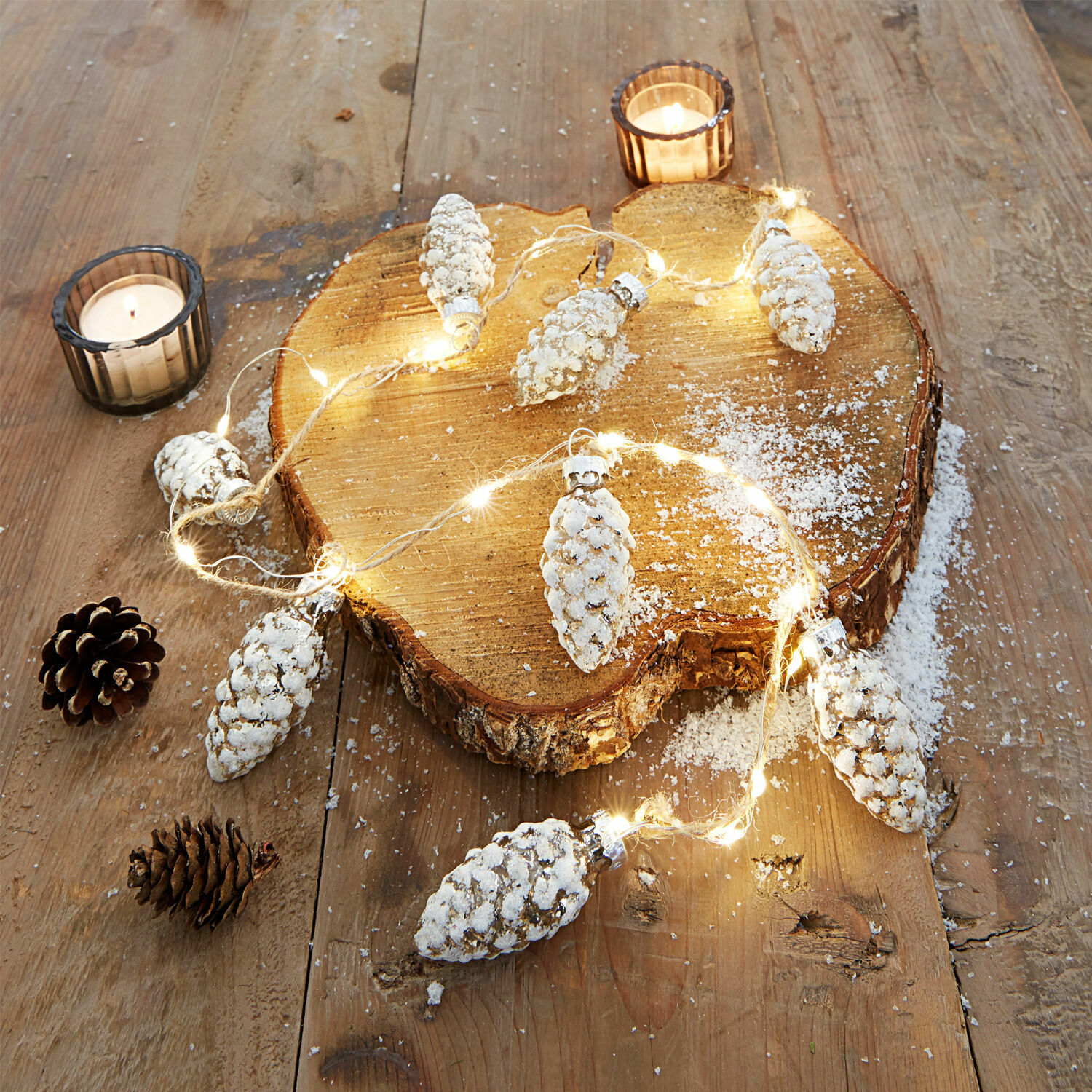 Lichtsnoer met dennenappels met witte sneeuwlook op houten plank, kerstdecoratie