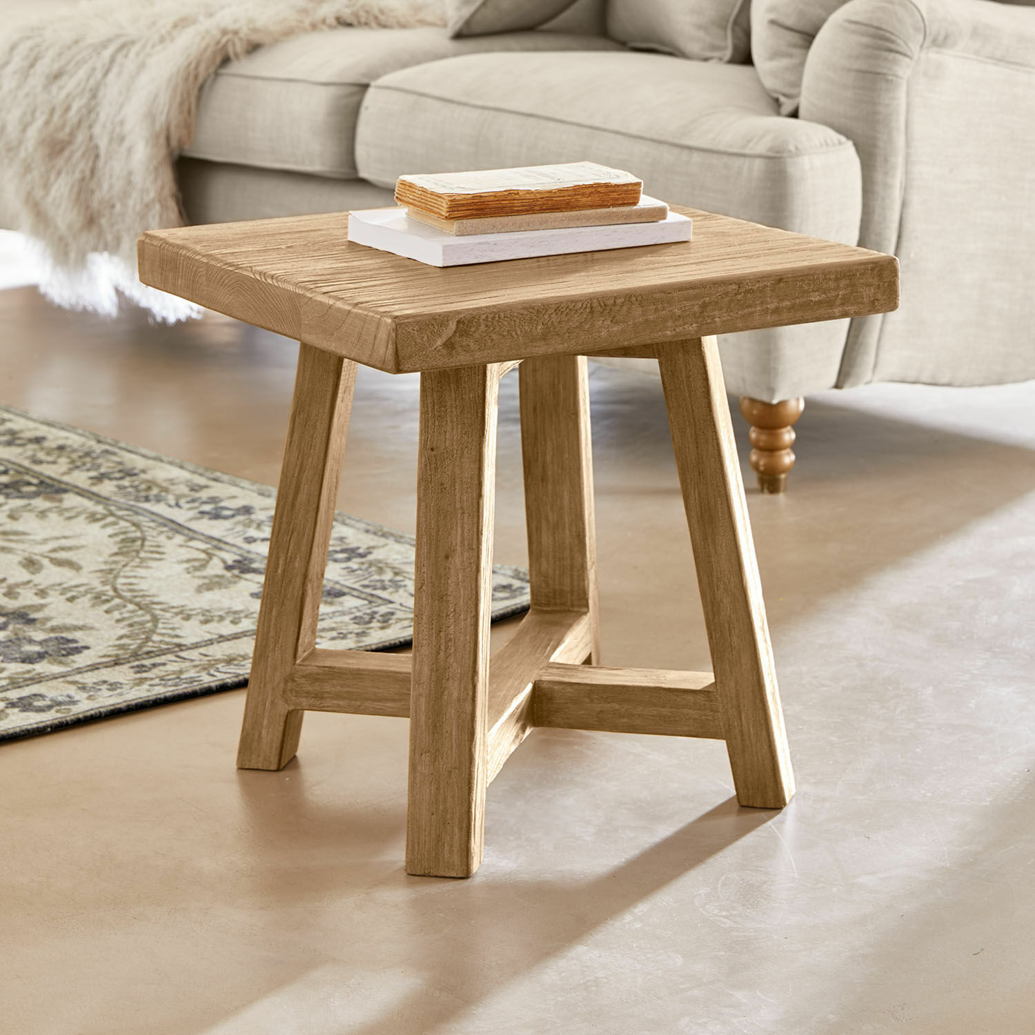 Vierkante salontafel van natuurlijk hout voor een beige bank en een decoratief vloerkleed