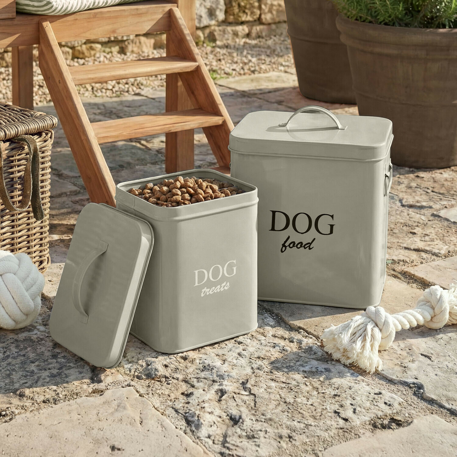 Grijze metalen bakken voor hondenvoer en traktaties op stenen vloer in de tuin