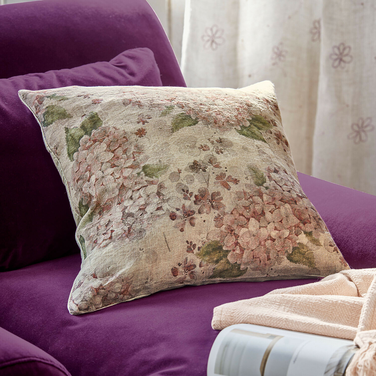 Decoratief linnen kussen met bloemenpatroon op paarse bank, gezellige woonaccessoire