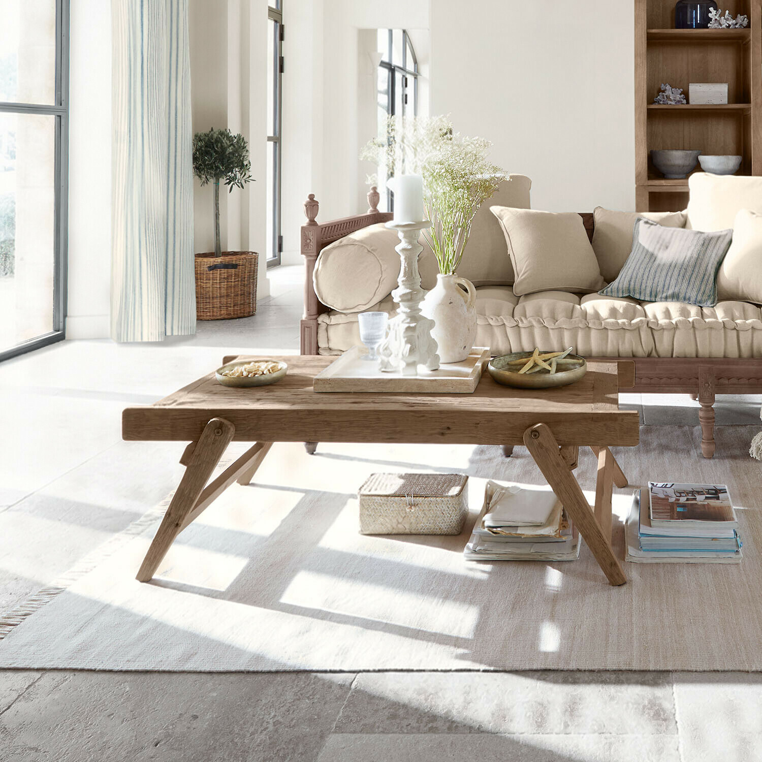 Houten salontafel met decoraties op lichte vloerkleed in gezellige woonkamer met beige bank