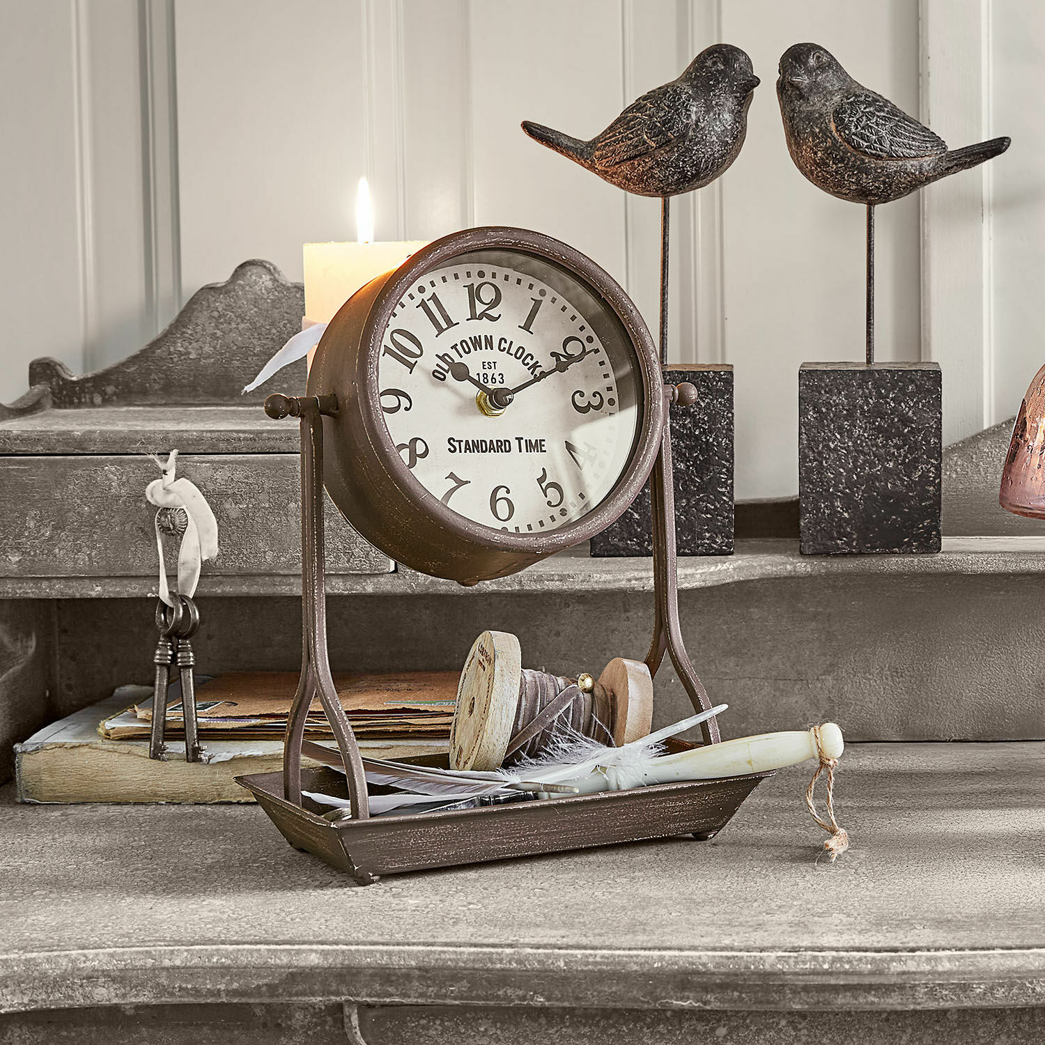 Klok Vorexil Vintage metalen tafelklok met witte wijzerplaat en zwarte cijfers op grijze decoratieve achtergrond