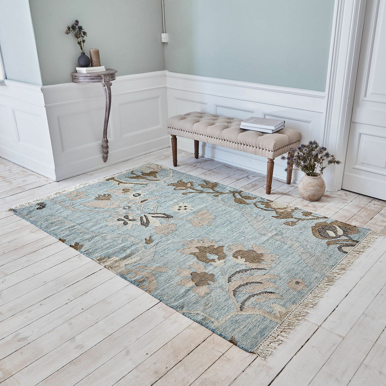 Vloerkleed Nére Katoenen vloerkleed in blauw en beige met bloemmotief op lichte houten vloer in woonkamer