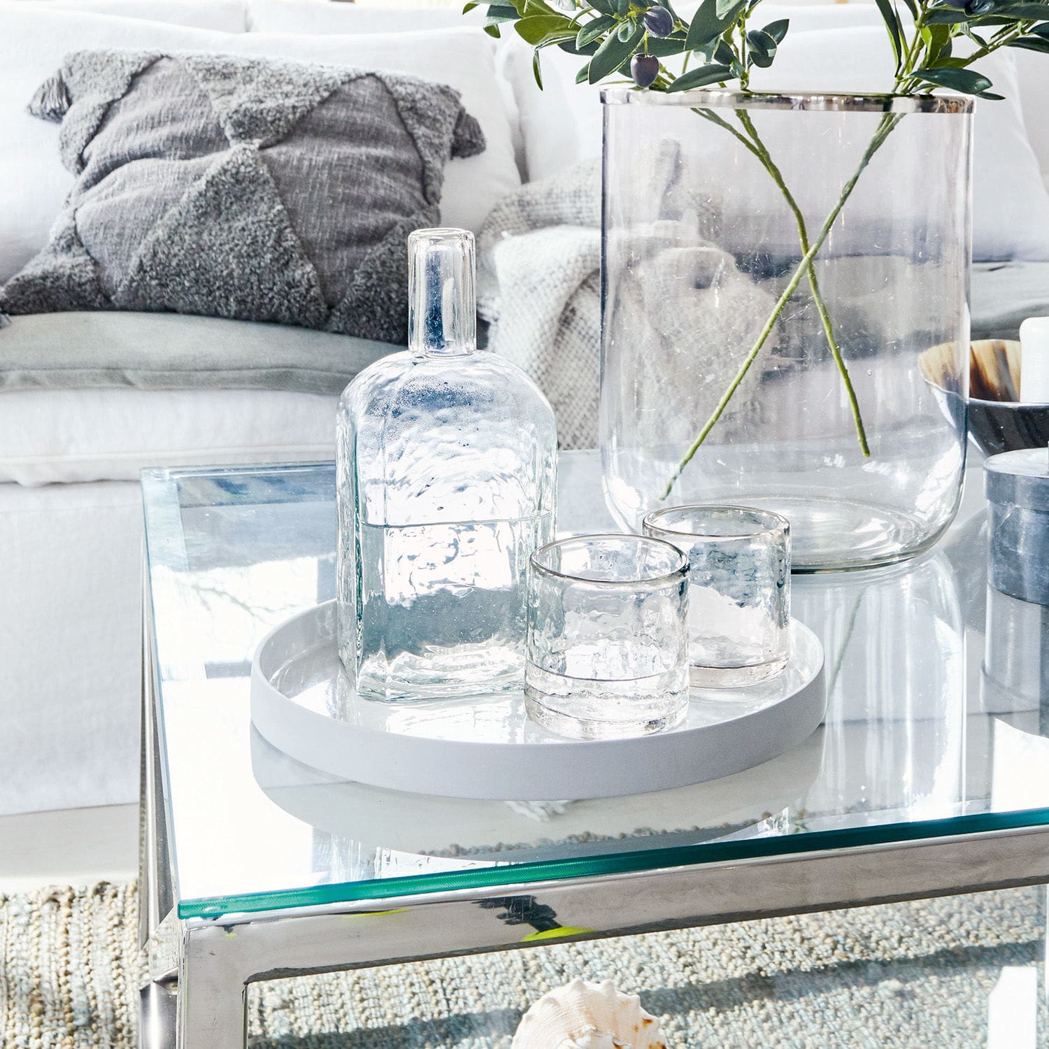 Glazen set met fles en twee glazen op wit dienblad op glazen tafel