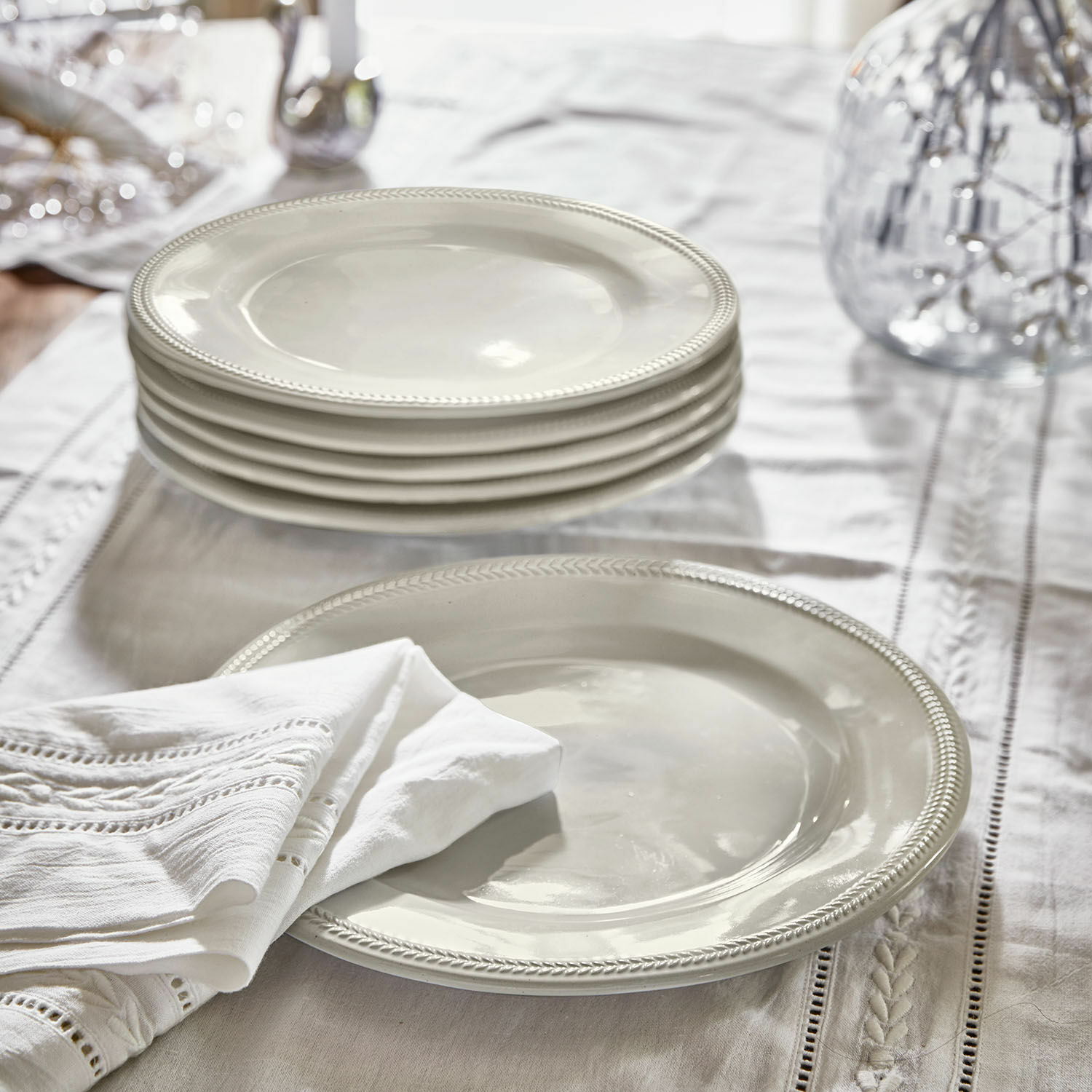 Set witte keramische borden met decoratieve rand op linnen tafelkleed, tafeldecoratie