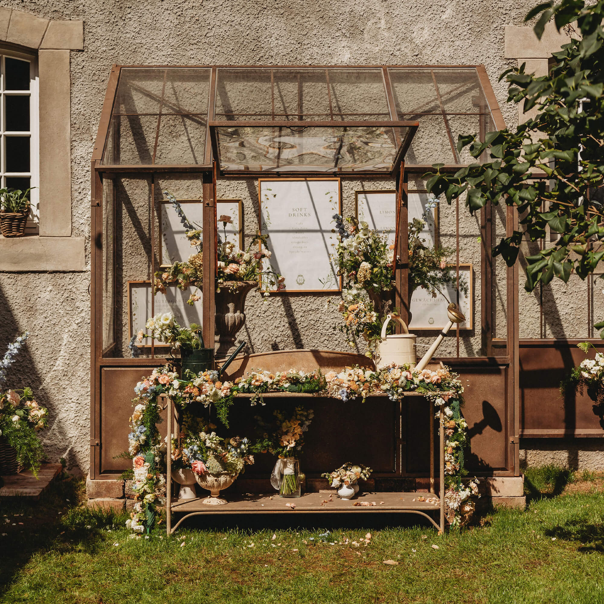 Metalen tuintafel met bloemen en gieters voor een glazen kas