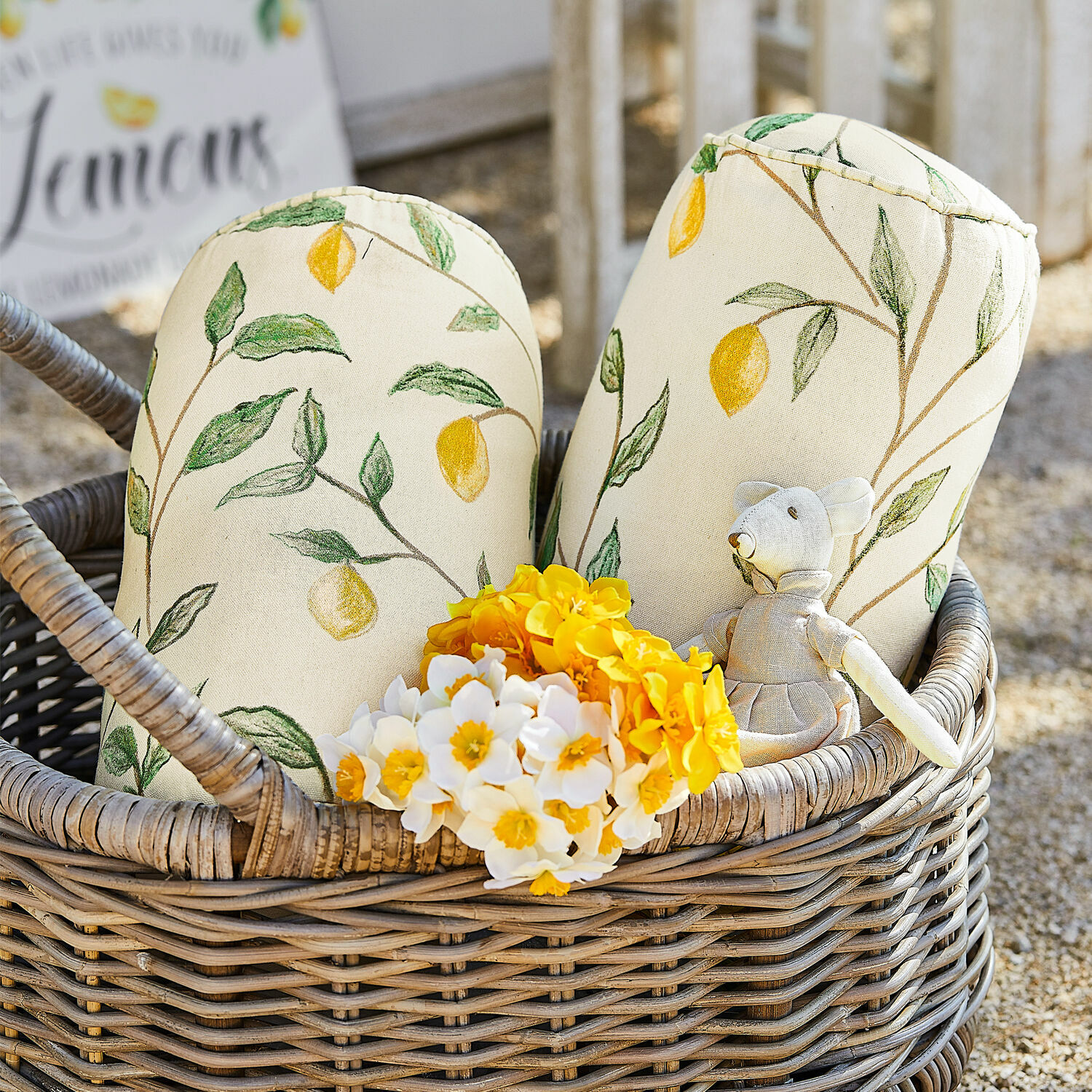Kussenrol set van 2 Palerina Decoratieve katoenen kussens in crème met citroenprint in een rieten mand met bloemen