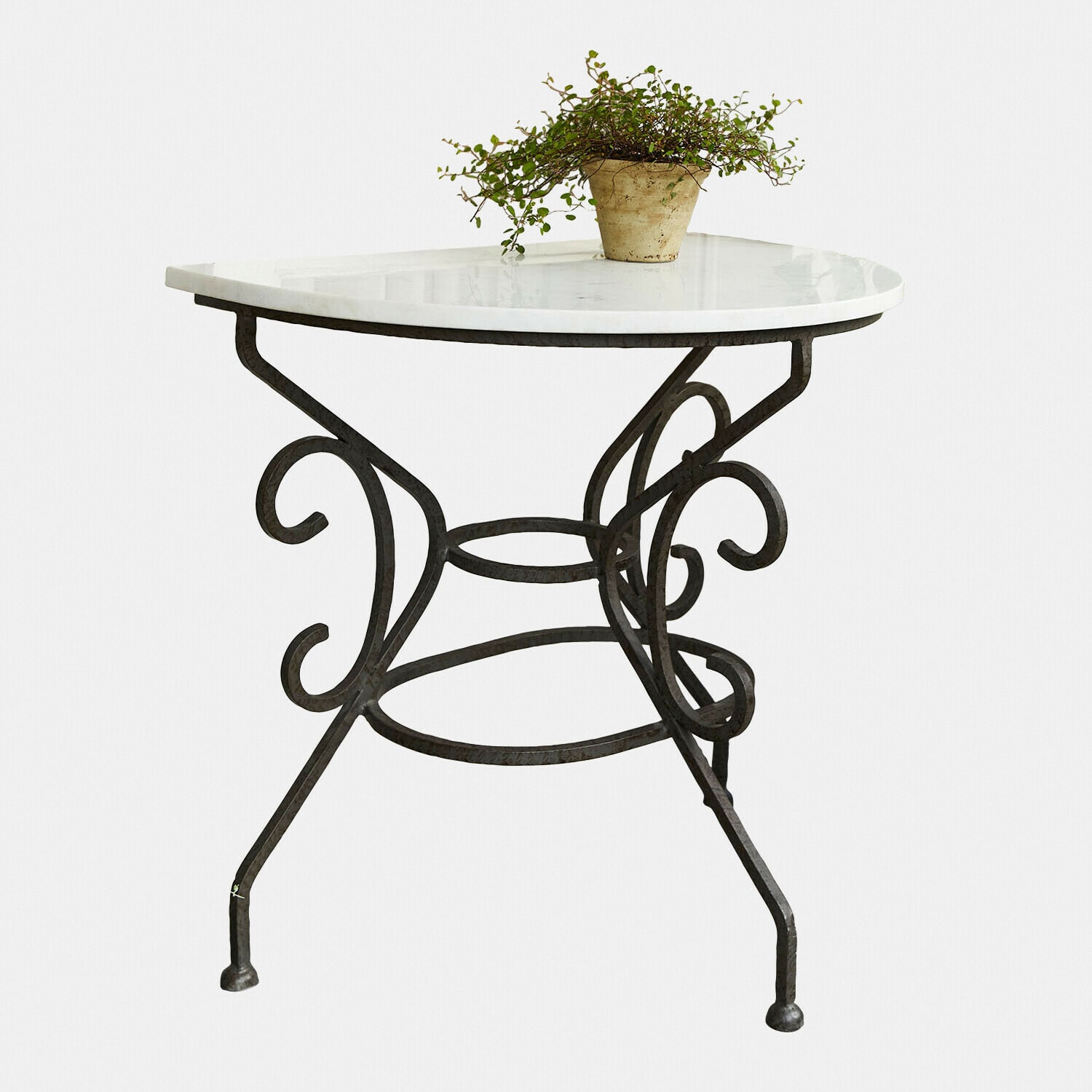 Tafel Vialette Ronde tafel met wit marmeren blad en zwart gesmeed metalen onderstel, decoratieve plant erop