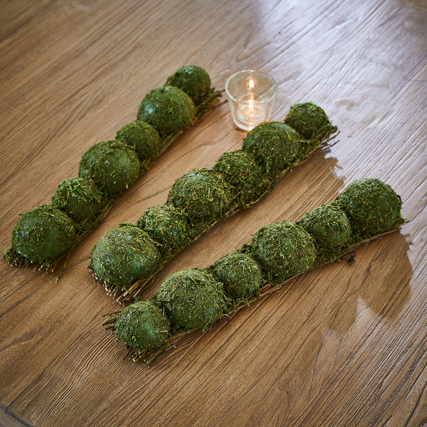 Tafeldecoratie van mos Cassiola Groene mosballen als decoratie op houten tafel met klein kaarsje, natuurlijke woondecoratie