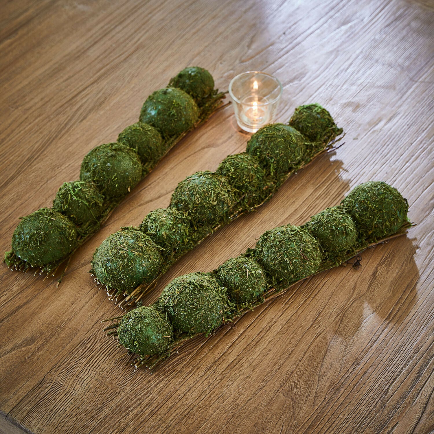 Tafeldecoratie van mos Cassiola Groene mosballen als decoratie op houten tafel met klein kaarsje, natuurlijke woondecoratie
