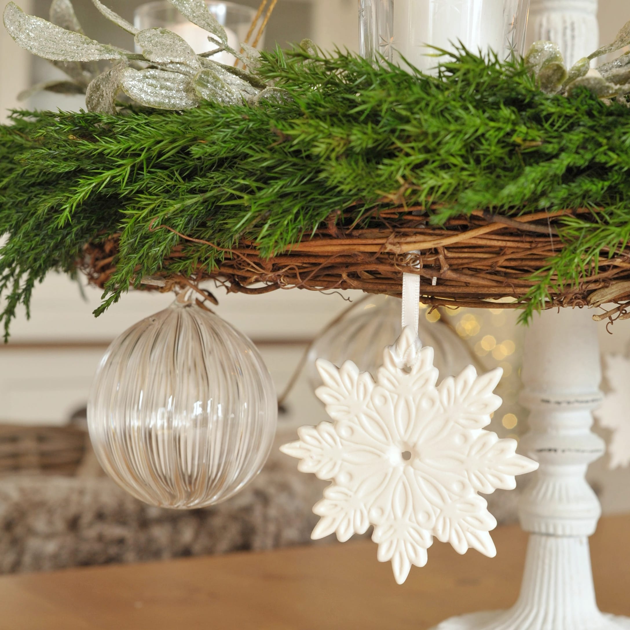Witte keramische sneeuwvlokhanger aan groene adventskrans met takken en glazen bal