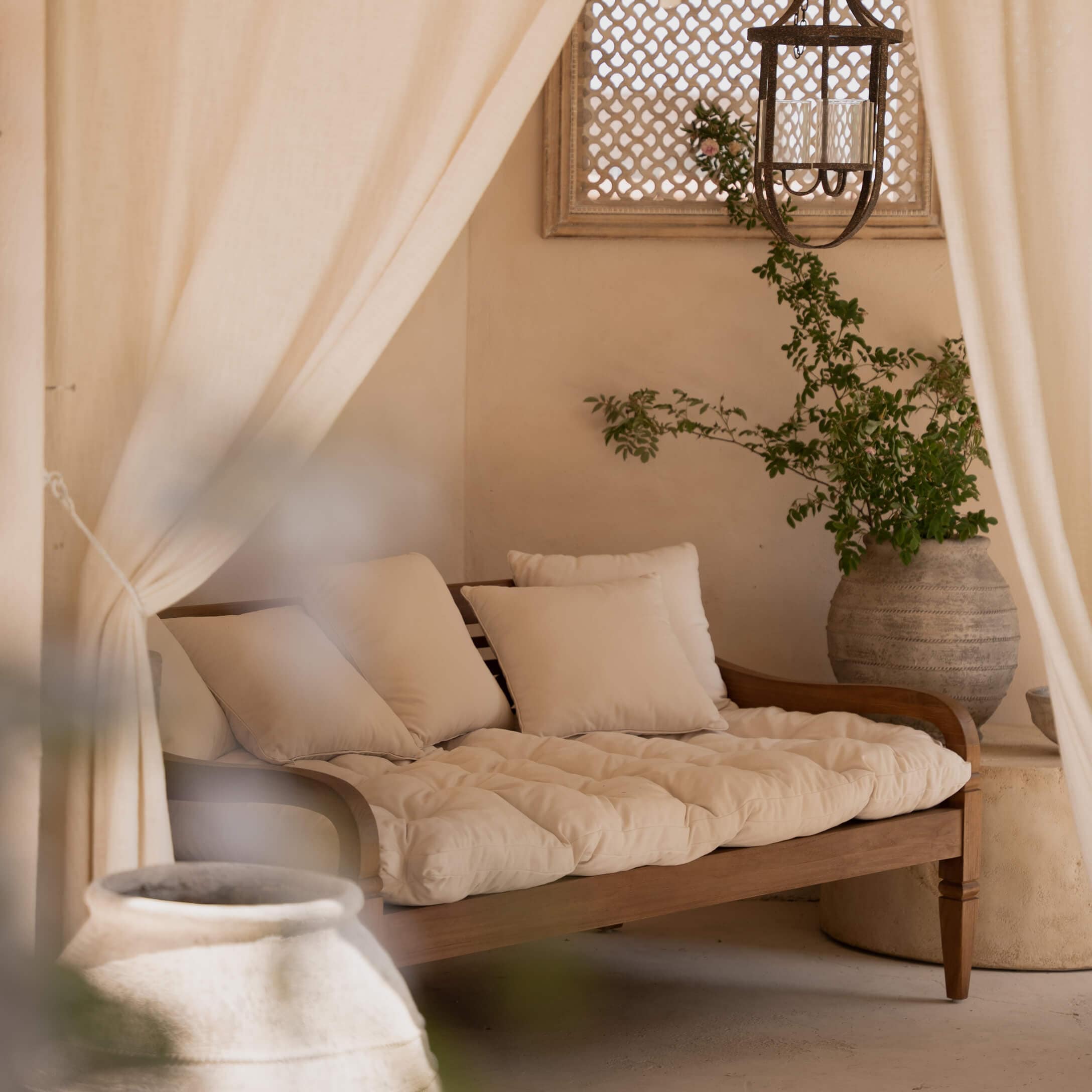 Houten bank met crèmekleurige kussens en zacht matras in een natuurlijke, gezellige ruimte
