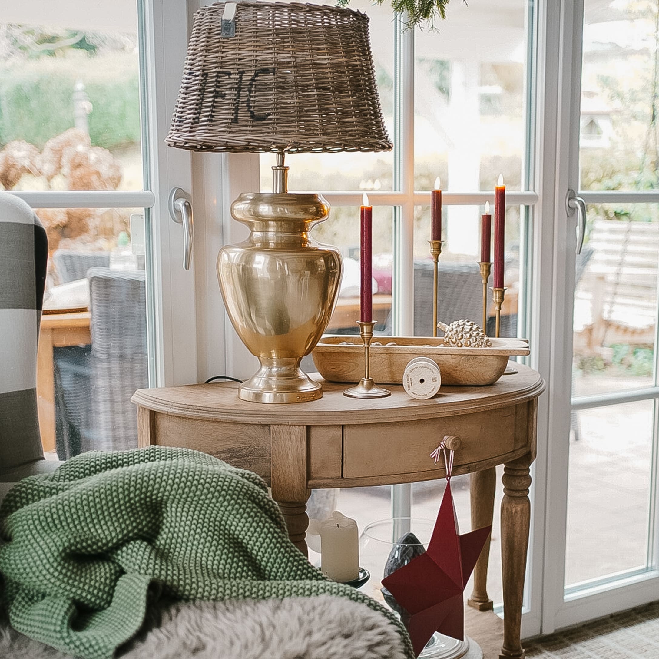 Houten tafel met messing lamp en rode kaarsen, kerstdecoratie in lichte woonkamer