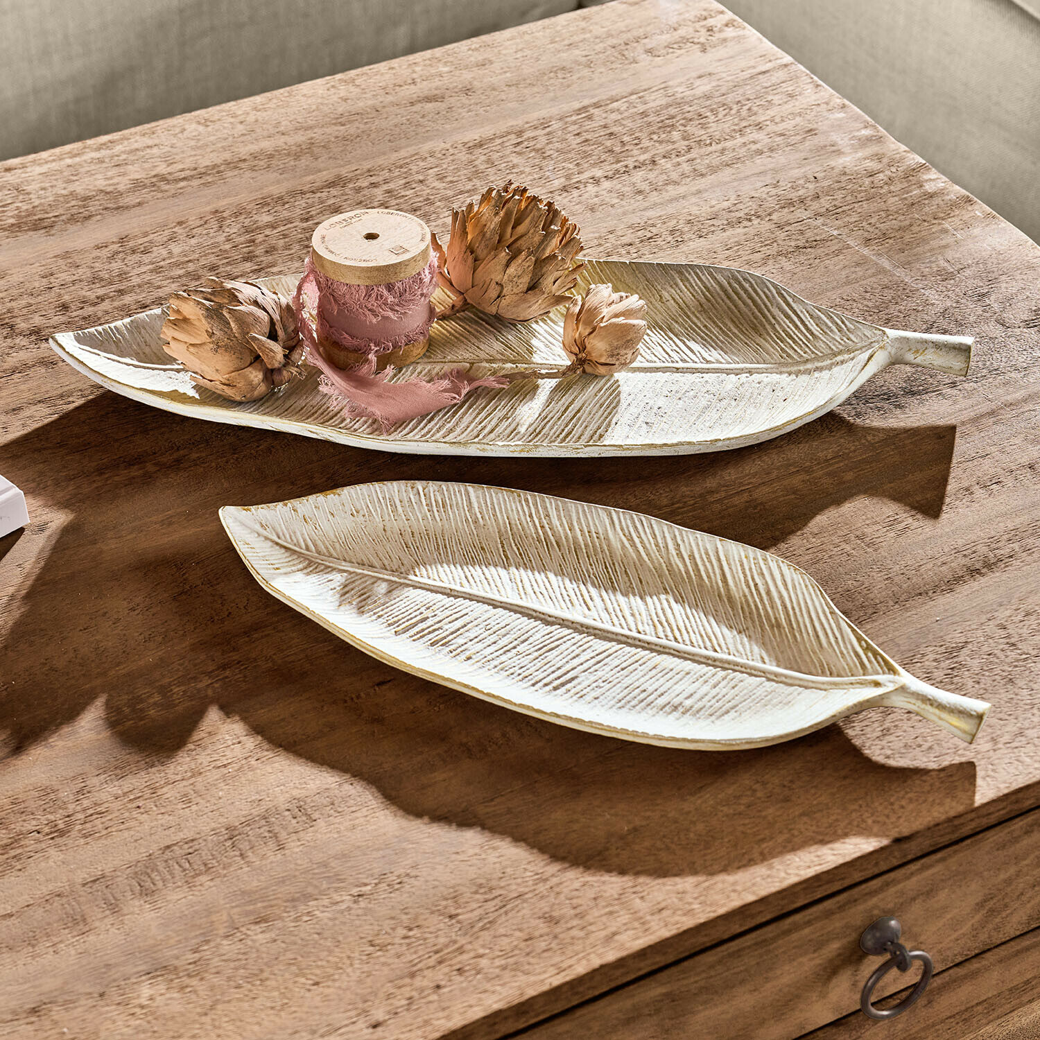 Decoratieve keramische borden in bladvorm crème kleur op houten tafel geplaatst