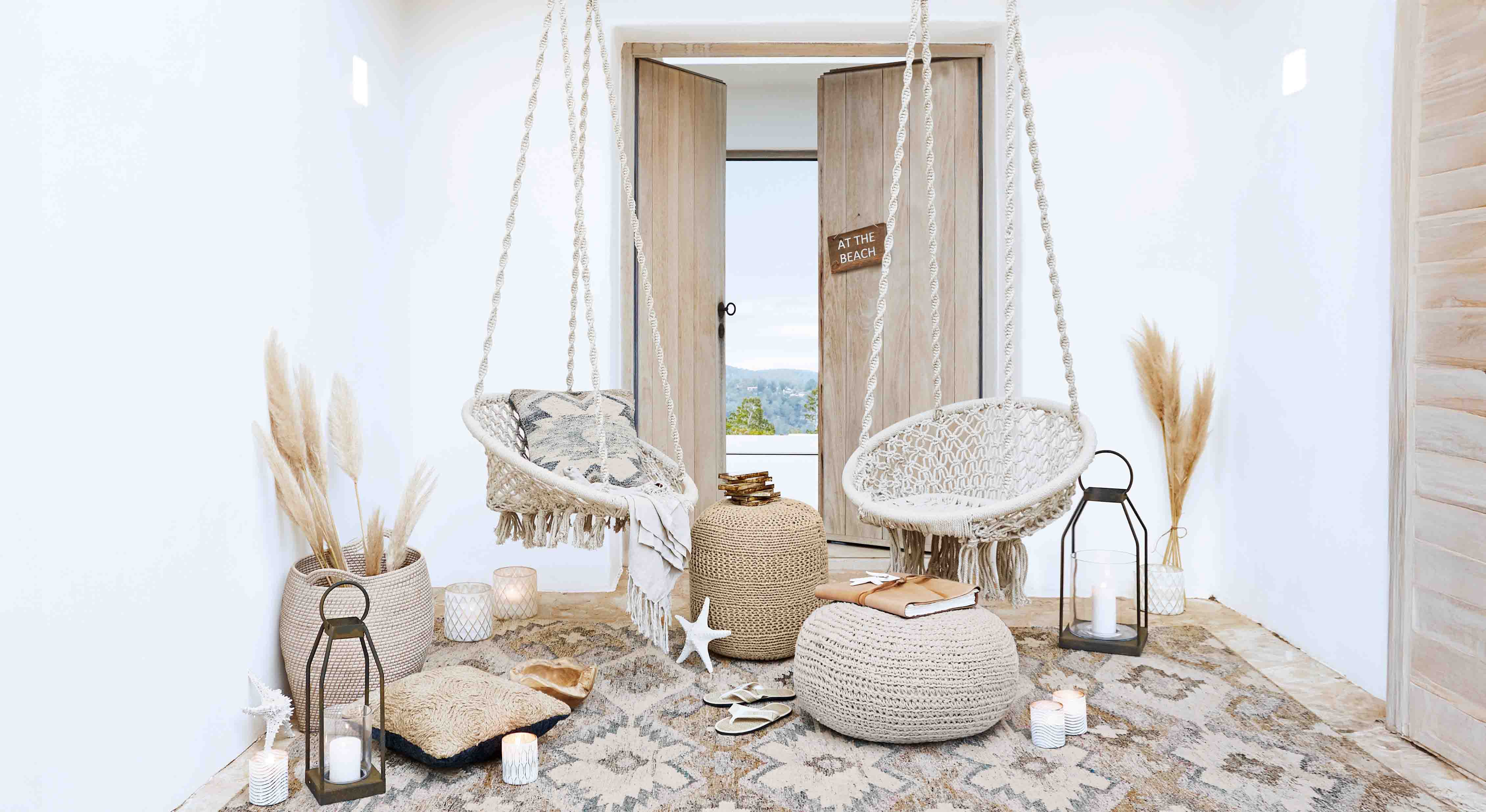 Gezellige woonkamer met witte hangstoelen van macramé en natuurlijke boho-decoraties